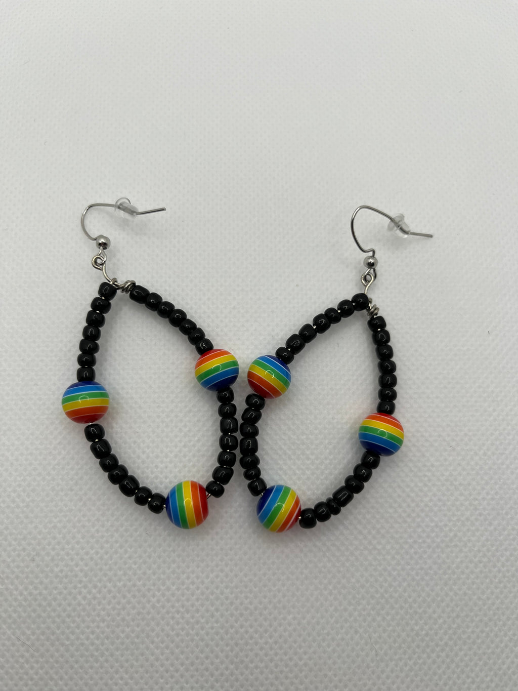 Black seed beads with rainbow beads throughout on earrings against a white background