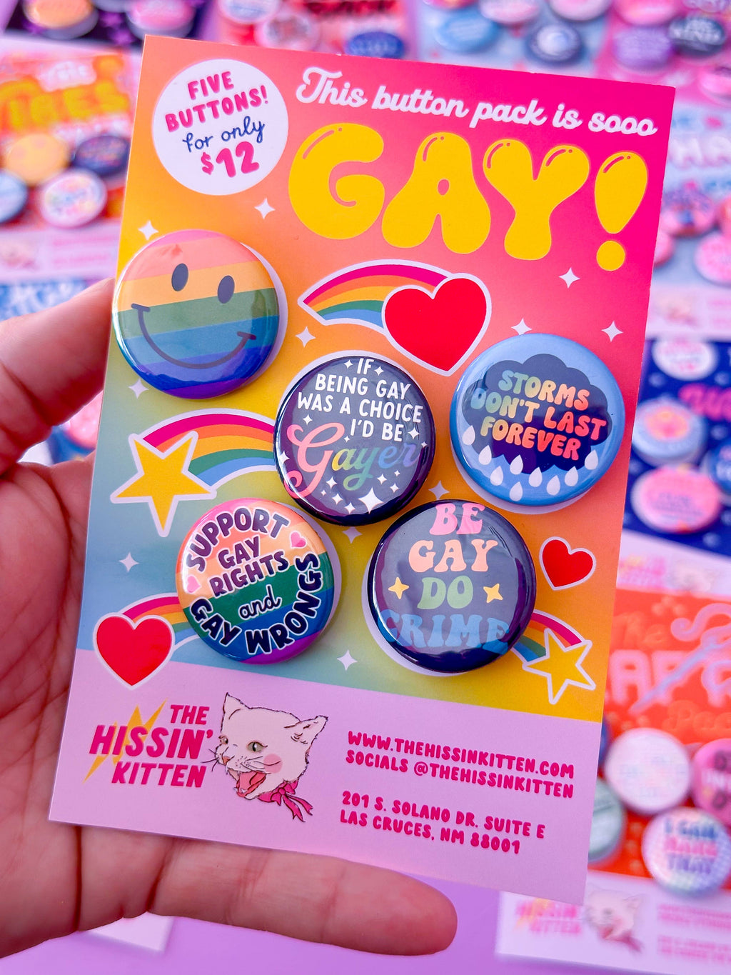 Button pack with colorful buttons and 'GAY!' text held by a hand against a colorful background.