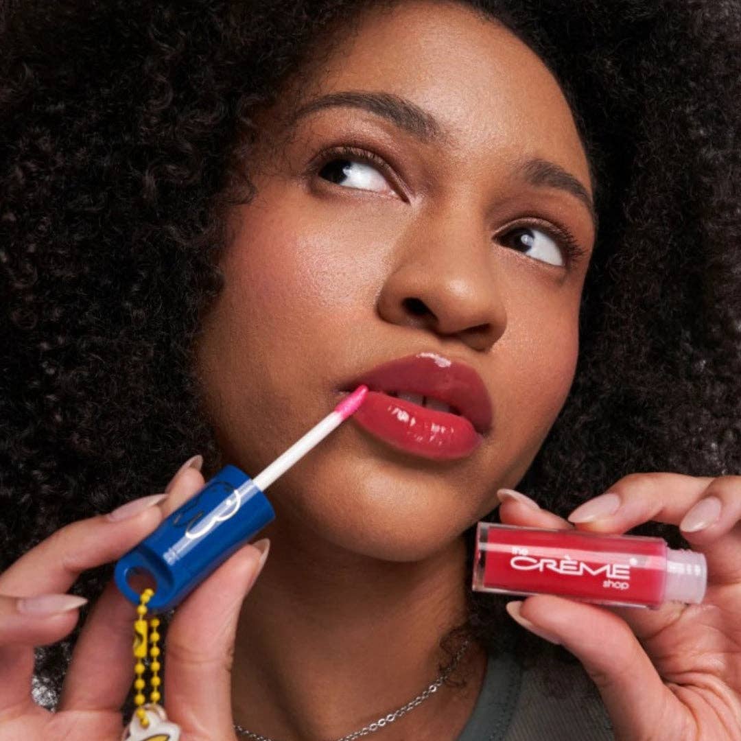 Woman applying a red lip oil with a blue applicator to her lips.