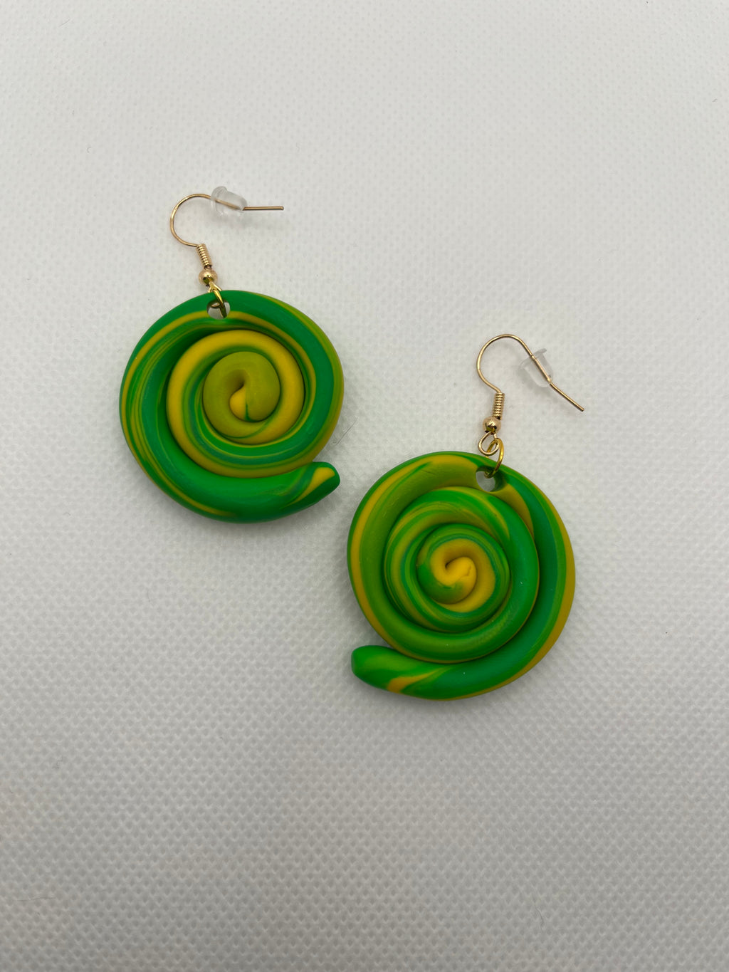 Green and yellow circle swirl earrings against a white background