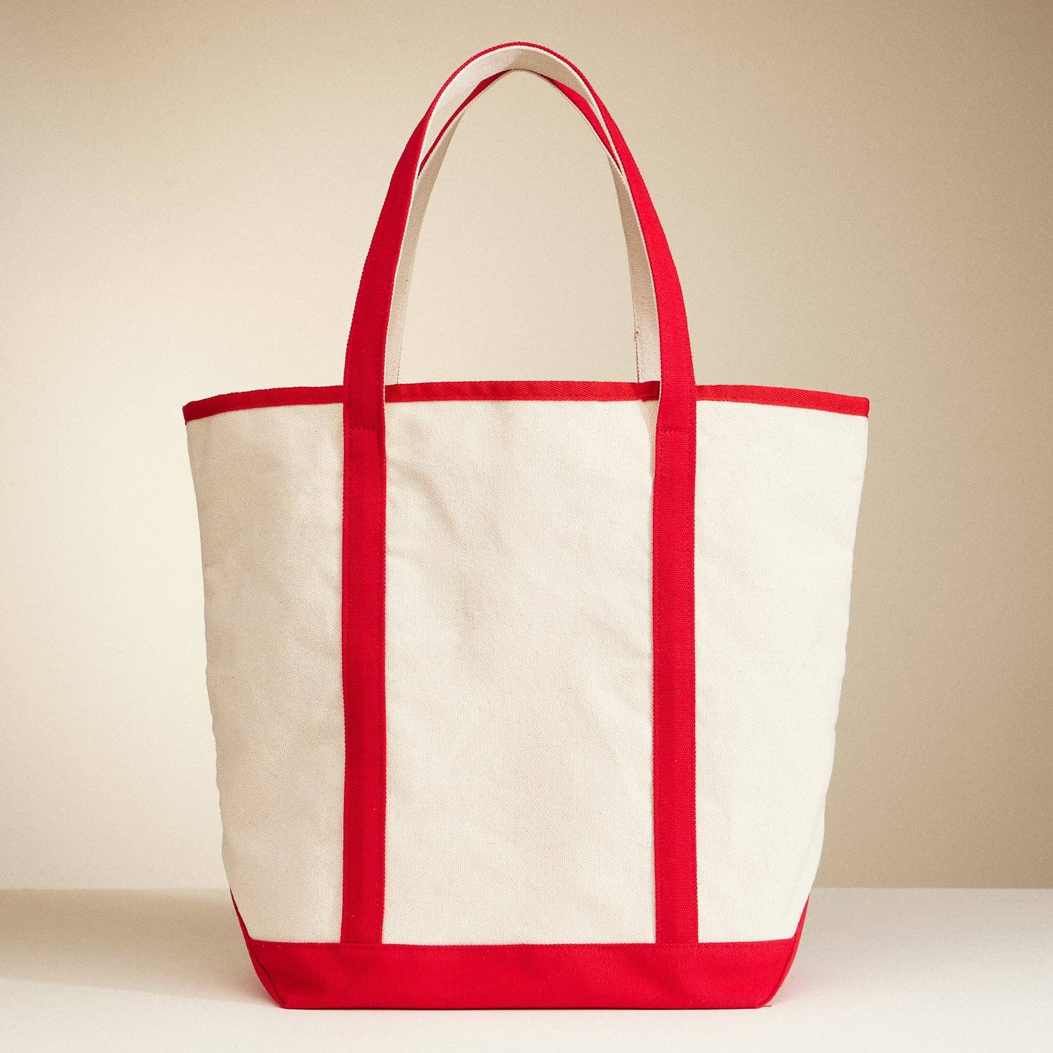 White tote bag with red trim on a beige background