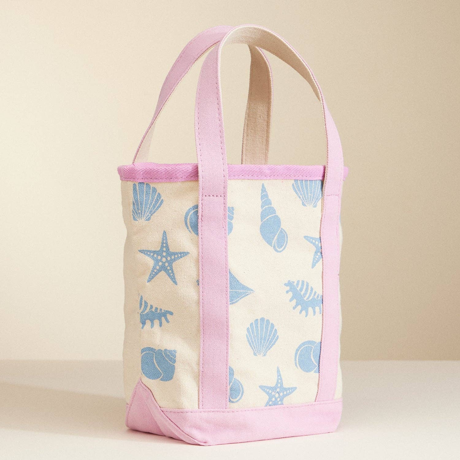 Tote bag with shell pattern and pink accents on a beige background