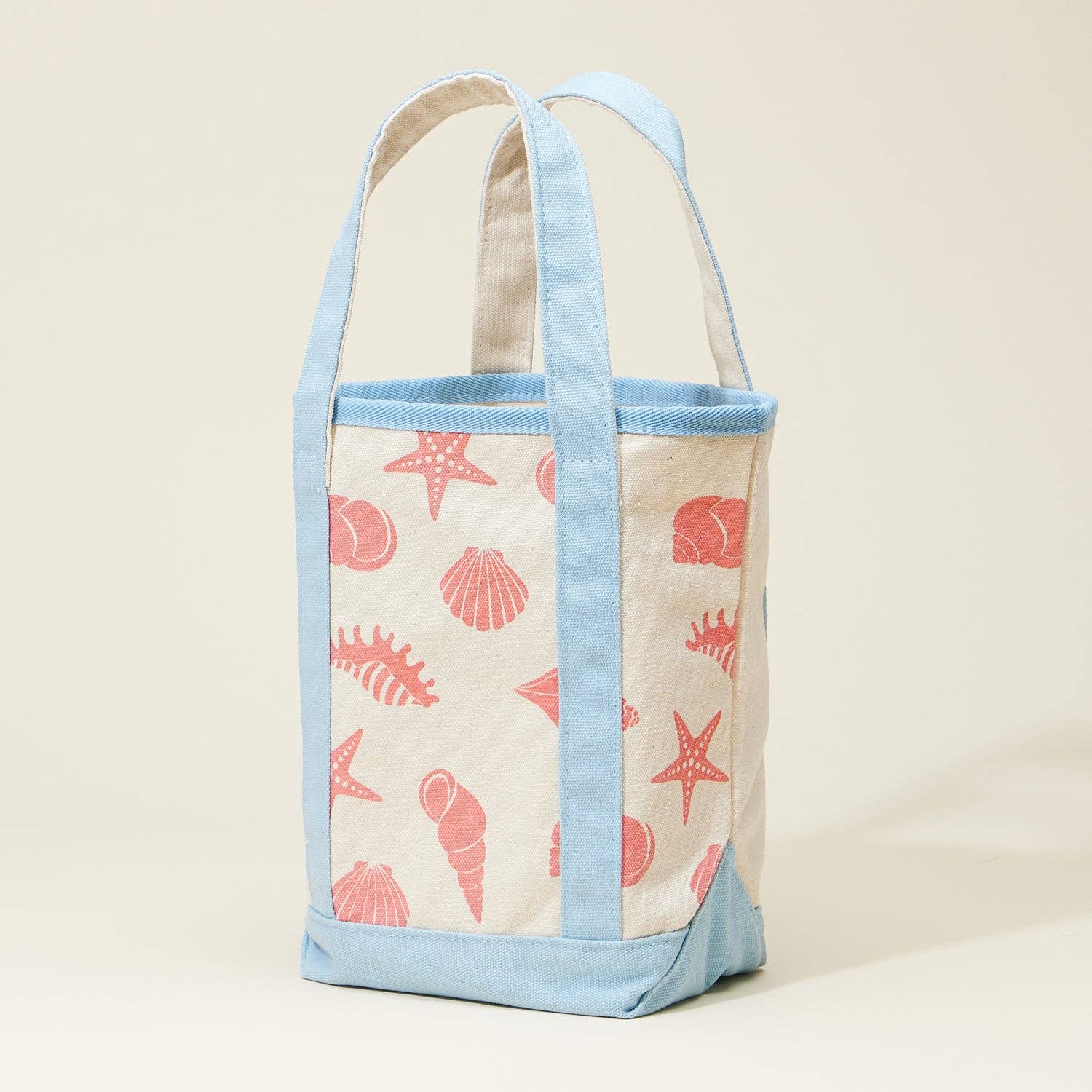 Tote bag with seashell pattern and light blue straps on a beige background