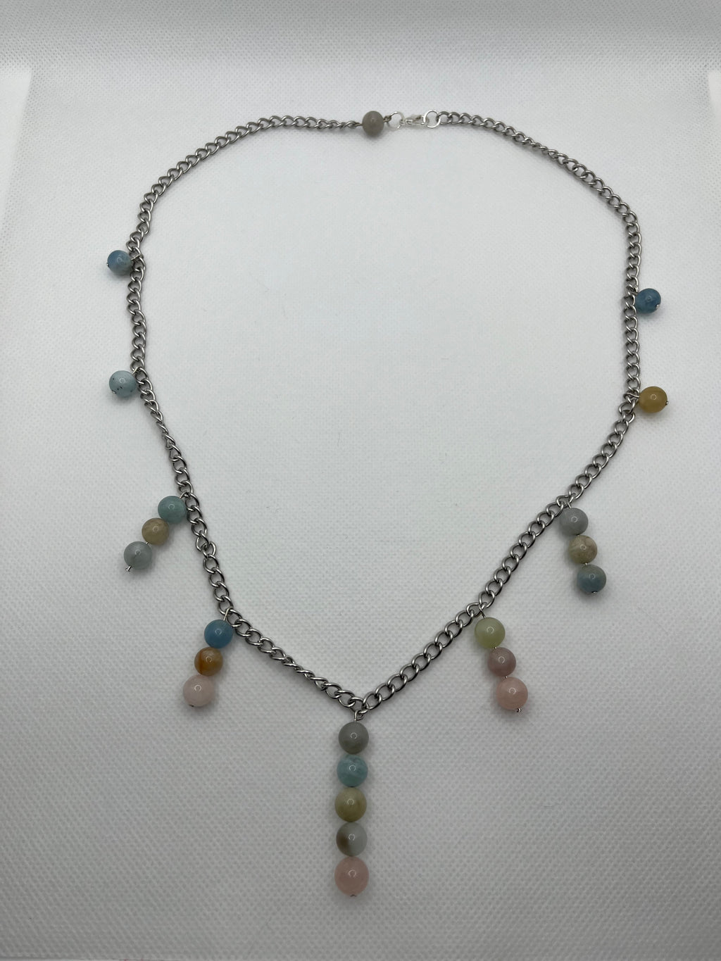 Necklace with multi-bead pastel pendants throughout laid flat against a white background.