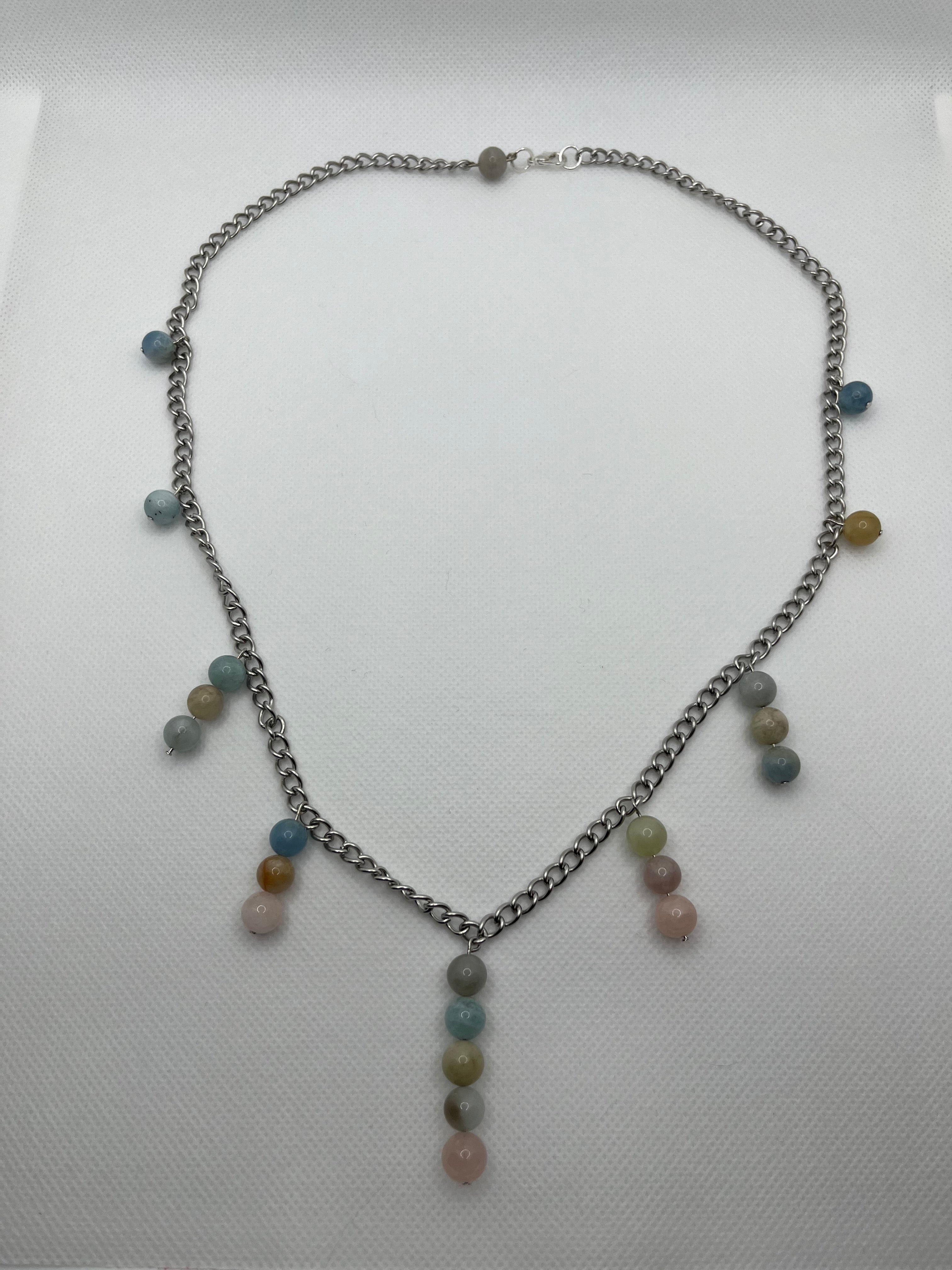 Necklace with multi-bead pastel pendants throughout laid flat against a white background.