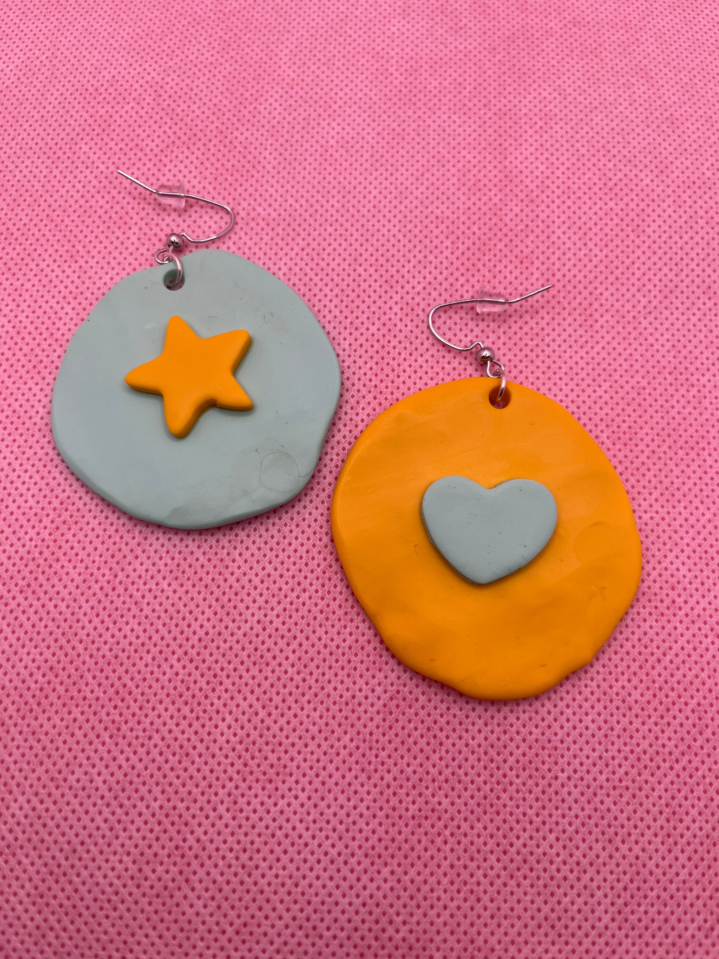 Mint and yellow large circle earrings with a star and heart against a pink background