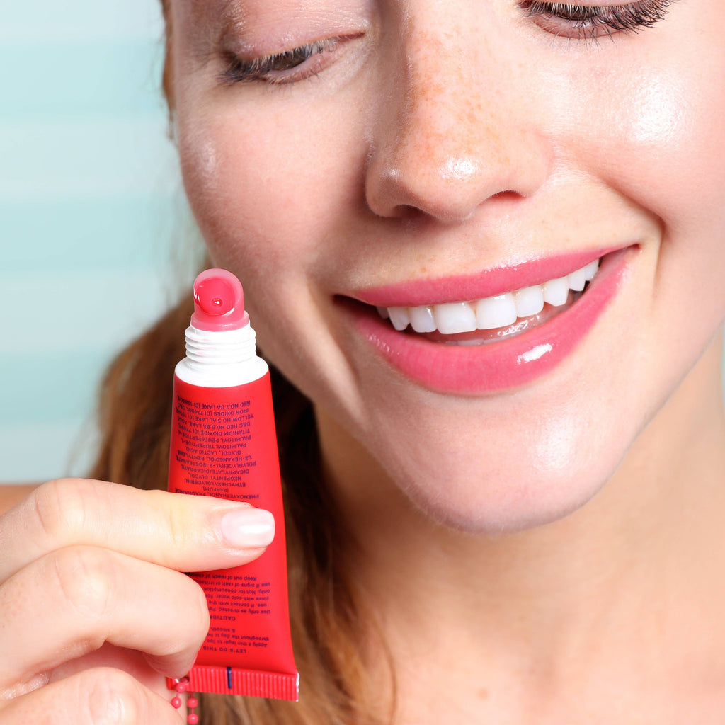Woman holding a red lip balm tube with a light blue background