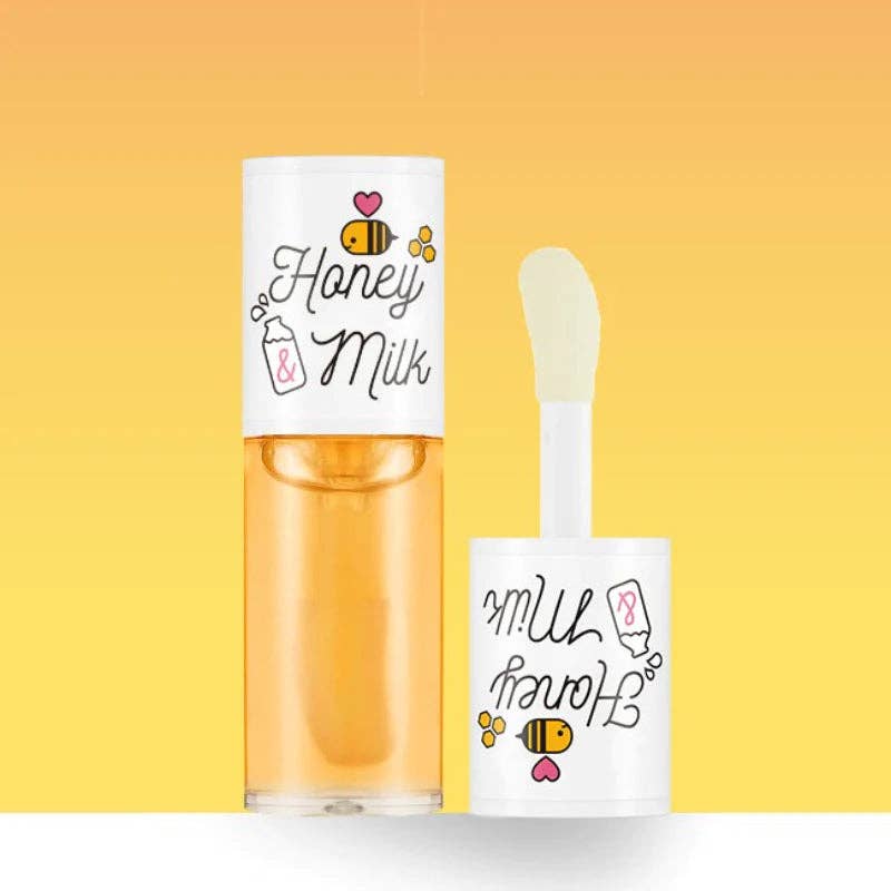 Yellow honey milk lip oil next to its applicator against a yellow background