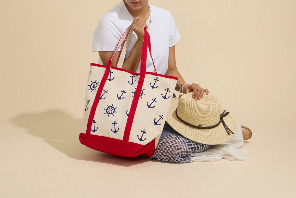 Person holding a tote bag with anchor pattern on a beige background