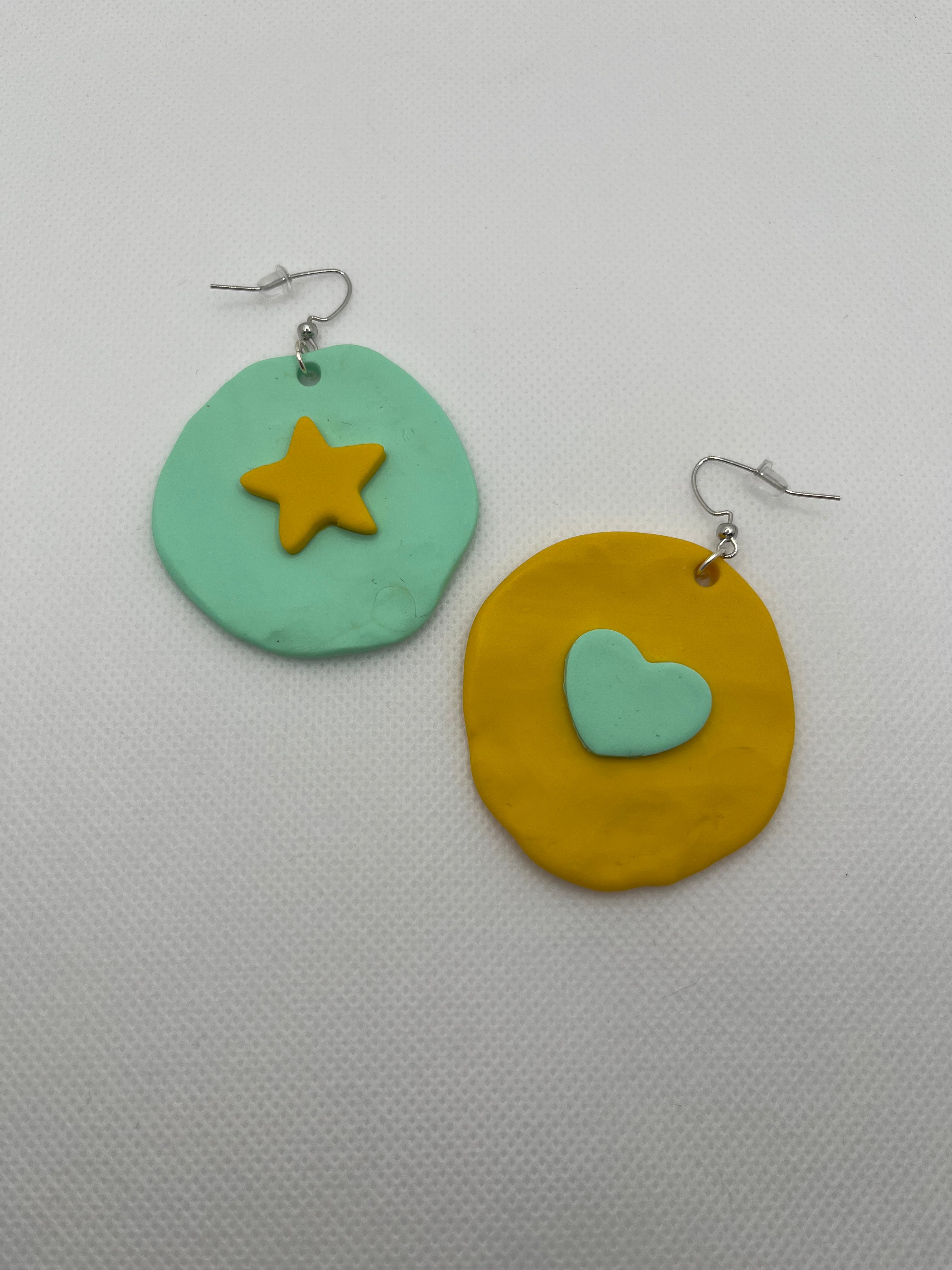 Mint and yellow large circle earrings with a star and heart against a white background