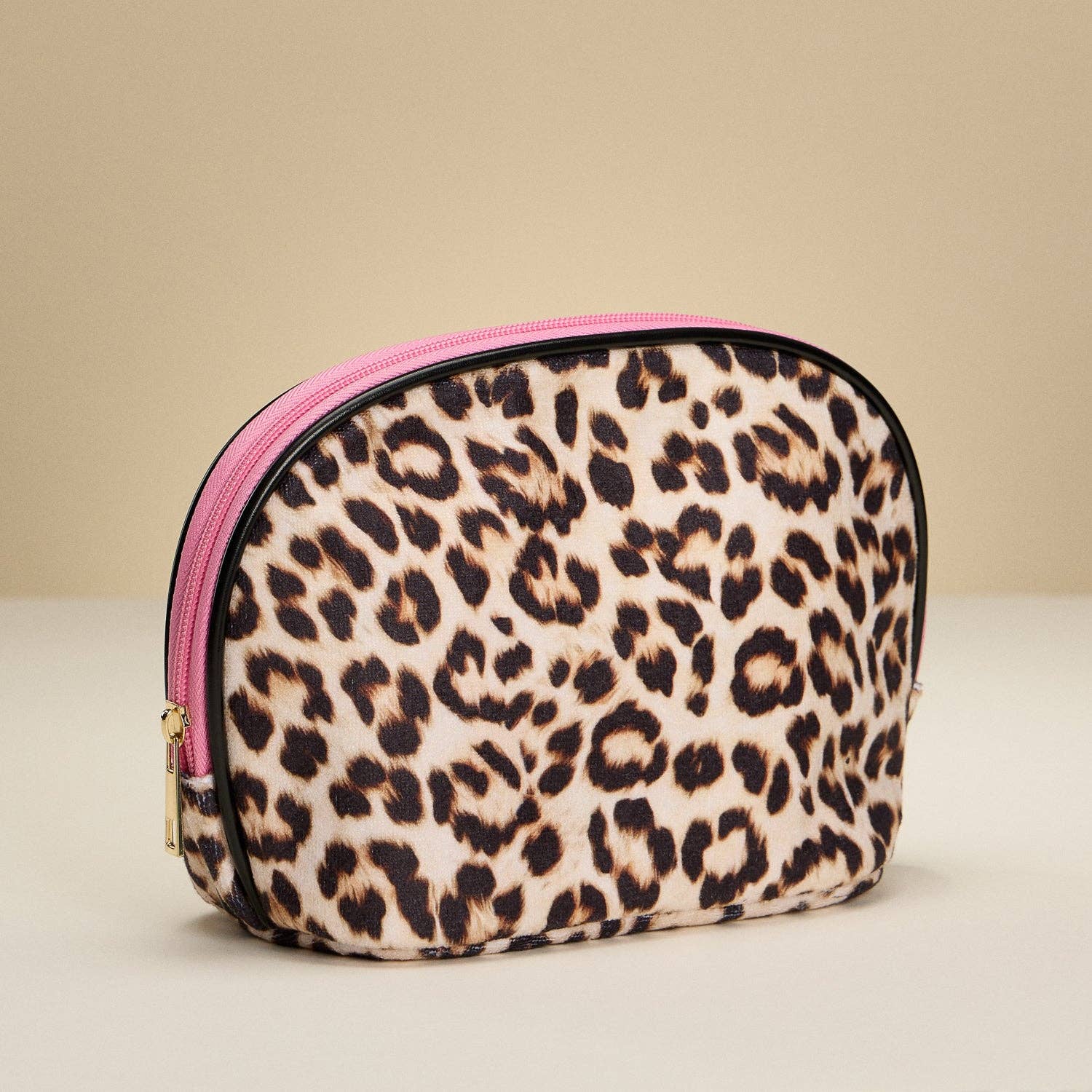 Leopard print makeup bag with pink zipper on a beige background