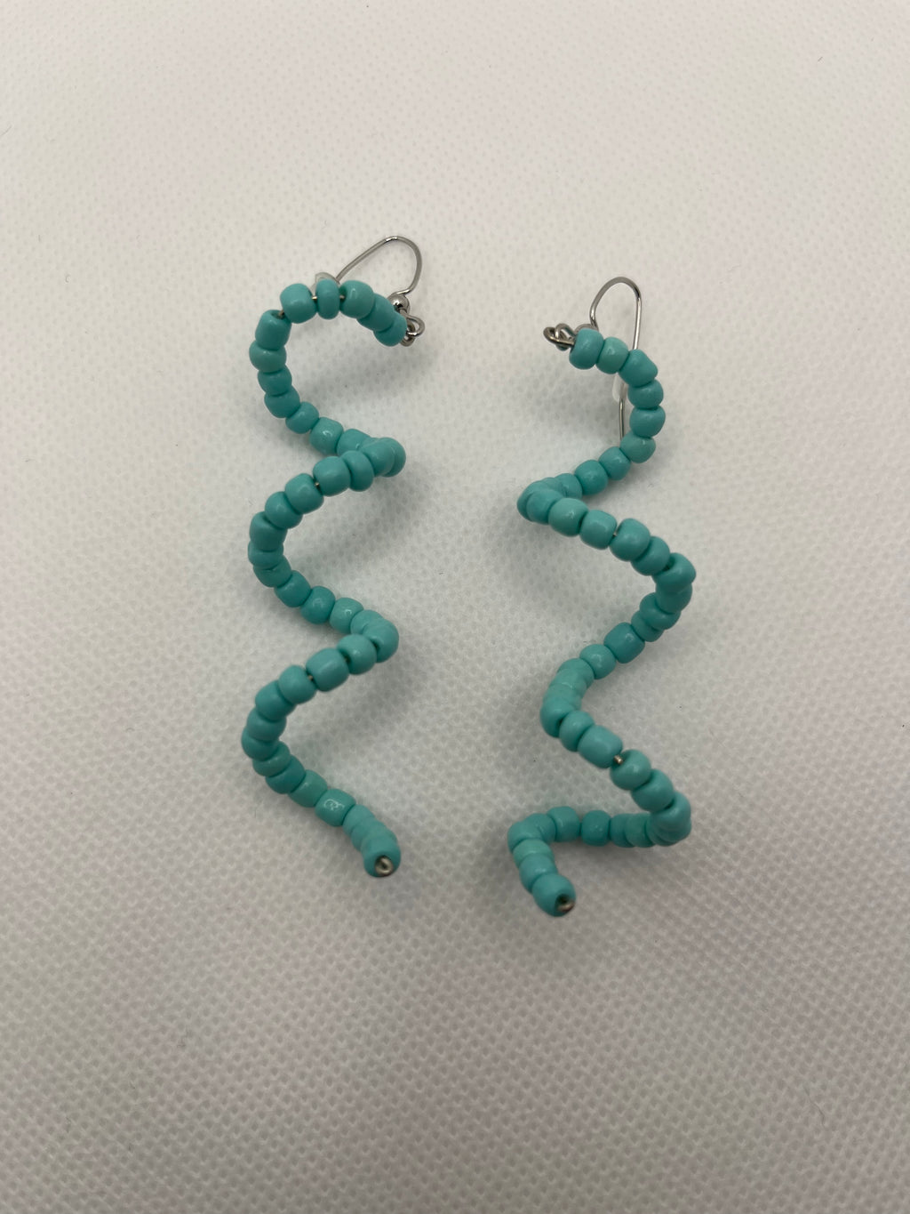 Light blue seed bead spiral earrings against a white background