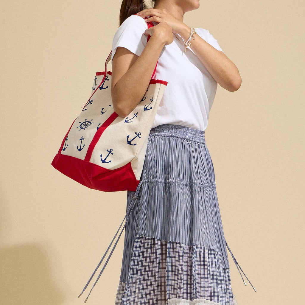 Person holding a tote bag with anchor pattern against a beige background