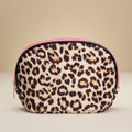 Leopard print pouch with pink zipper on a beige background