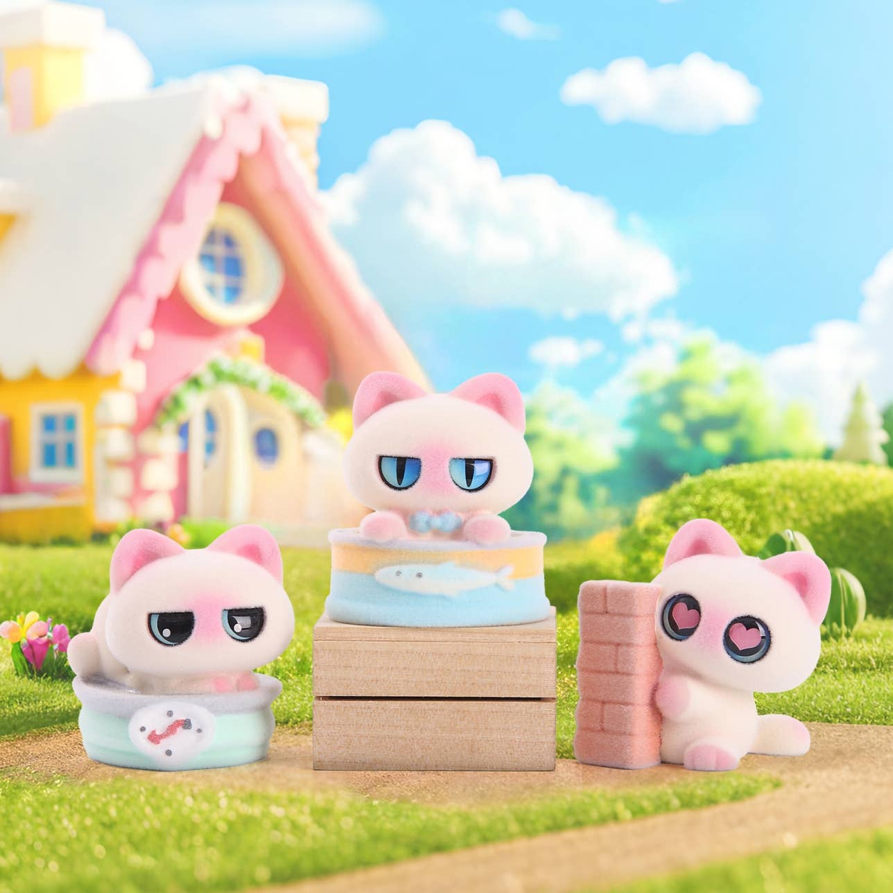 Three cartoon cat figurines in a colorful outdoor setting with a house in the background.