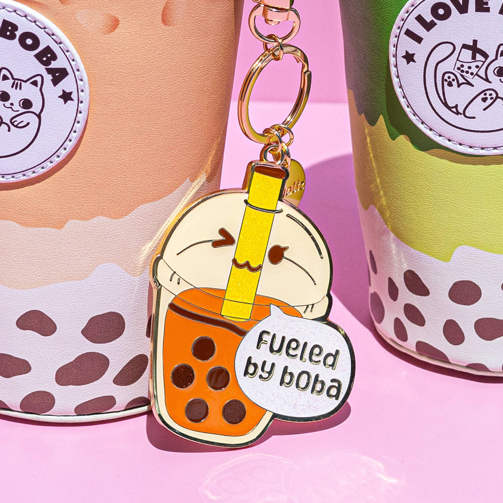Keychain shaped like a bubble tea with boba, placed on a pink background