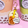 Keychain shaped like a bubble tea with boba, placed on a pink background