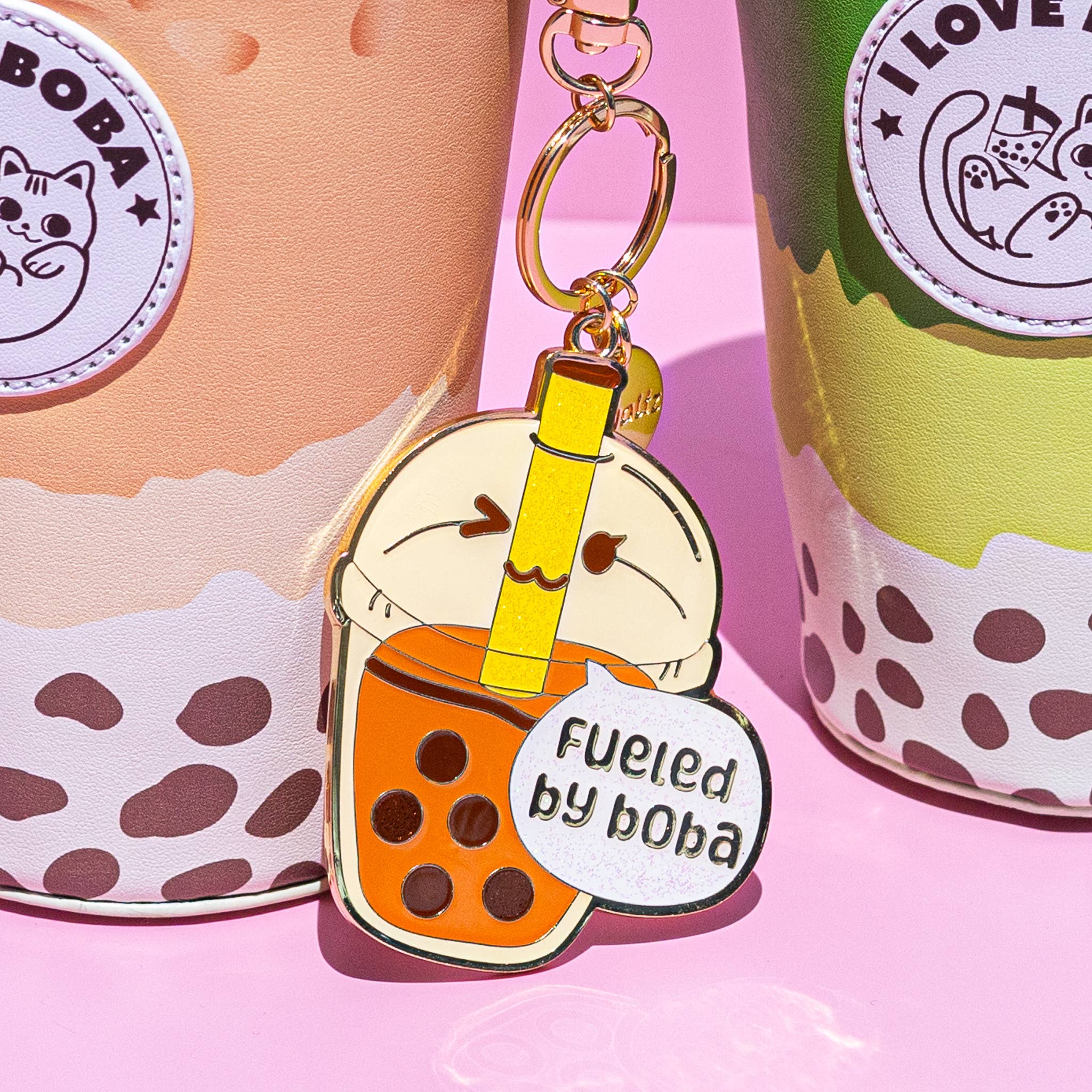 Keychain shaped like a bubble tea with boba, placed on a pink background