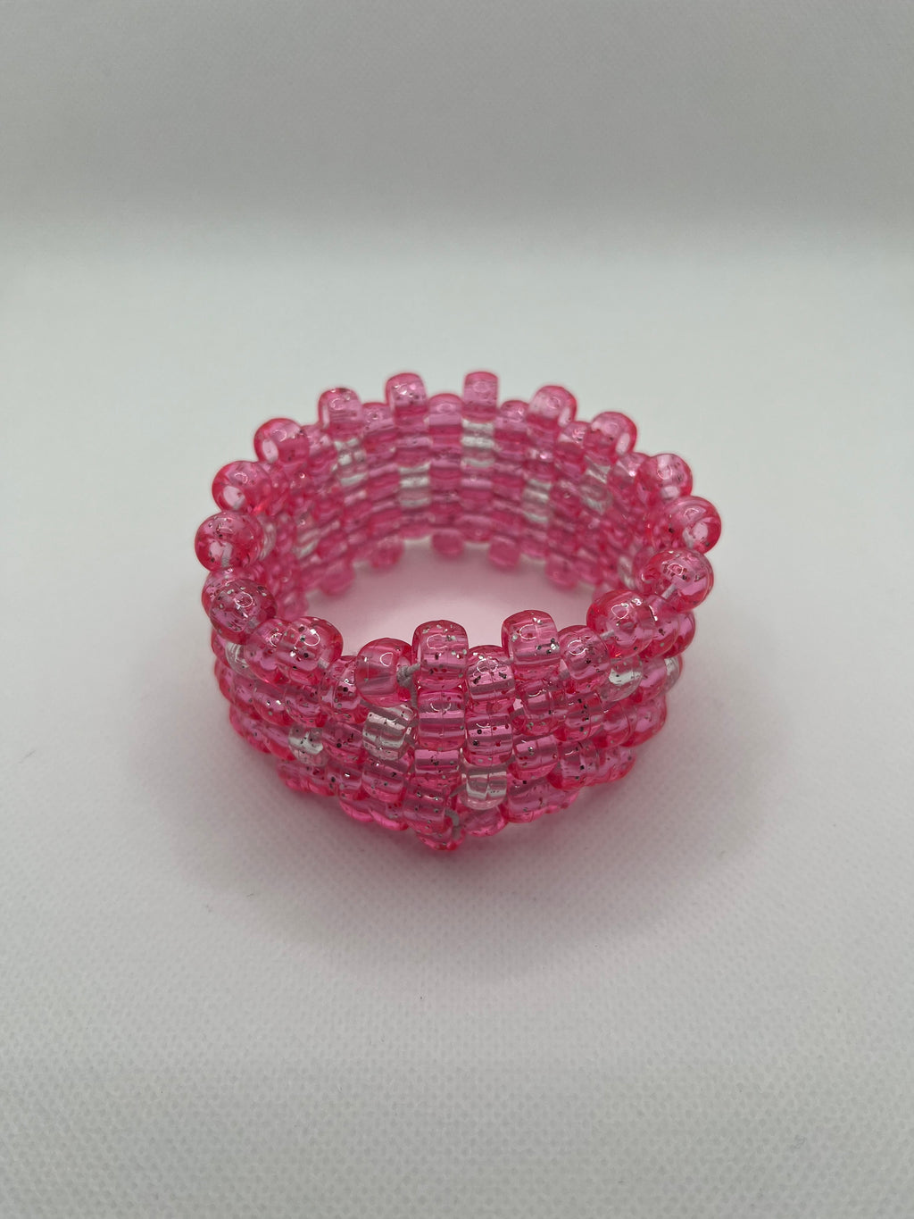 Pink glitter and clear beaded cuff bracelet on a white background.