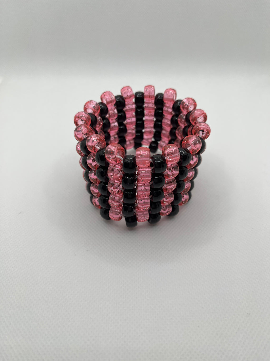 Pink glitter and black stripe beaded cuff bracelet on a white background.