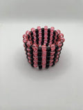 Pink glitter and black stripe beaded cuff bracelet on a white background.