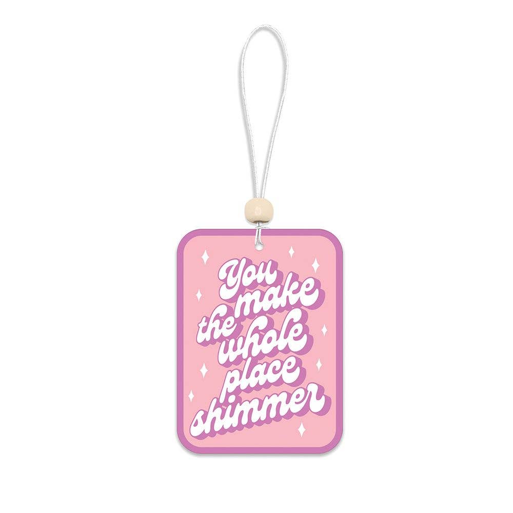 Pink car air freshener with white text on a white background