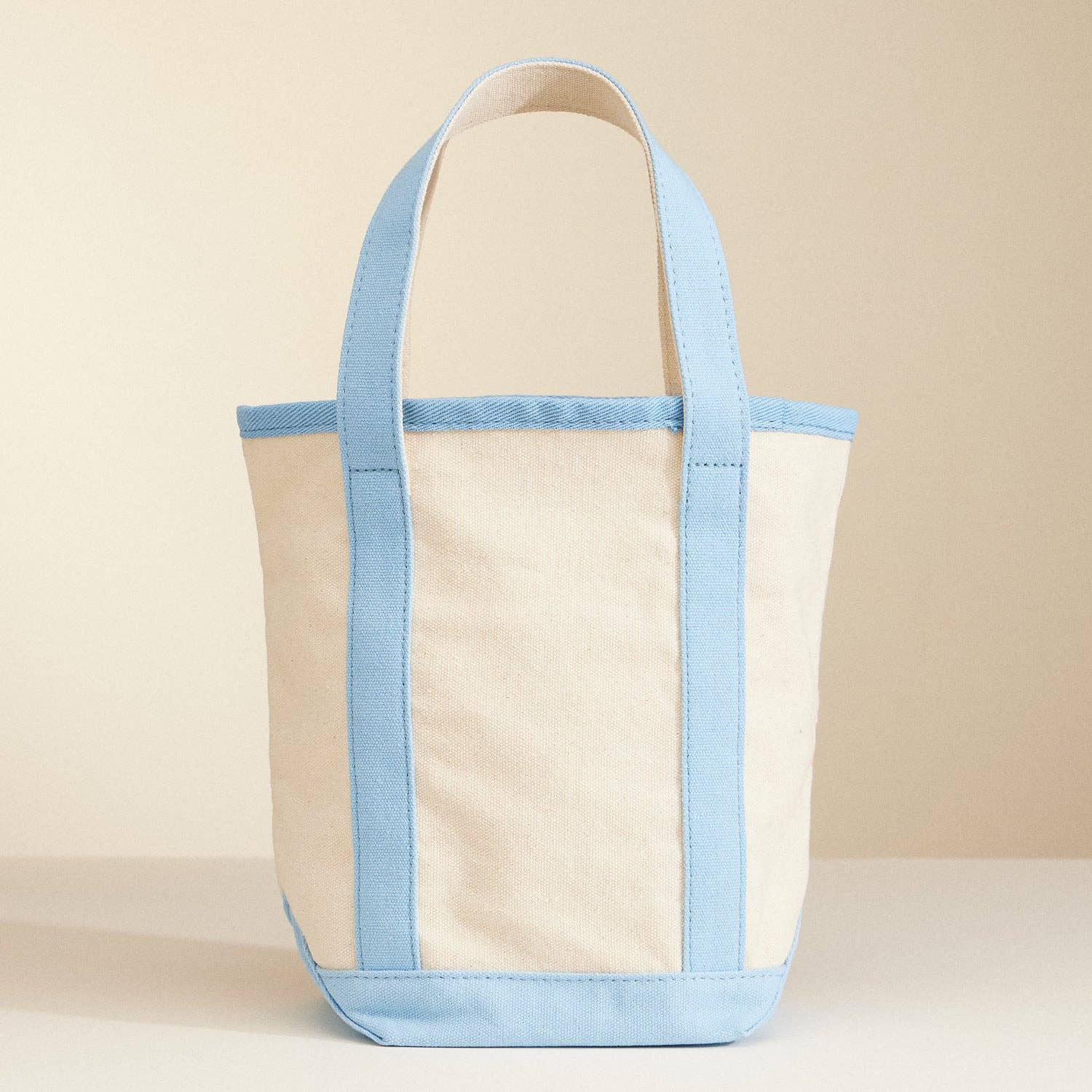 Beige tote bag with light blue accents on a beige background