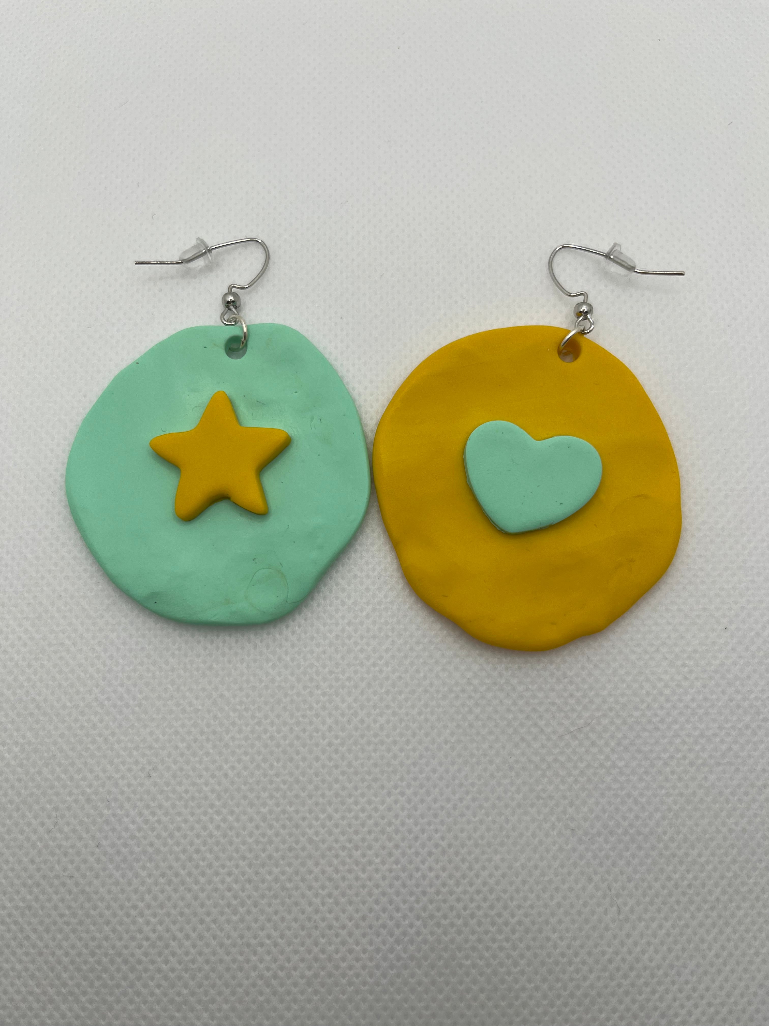 Mint and yellow large circle earrings with a star and heart against a white background