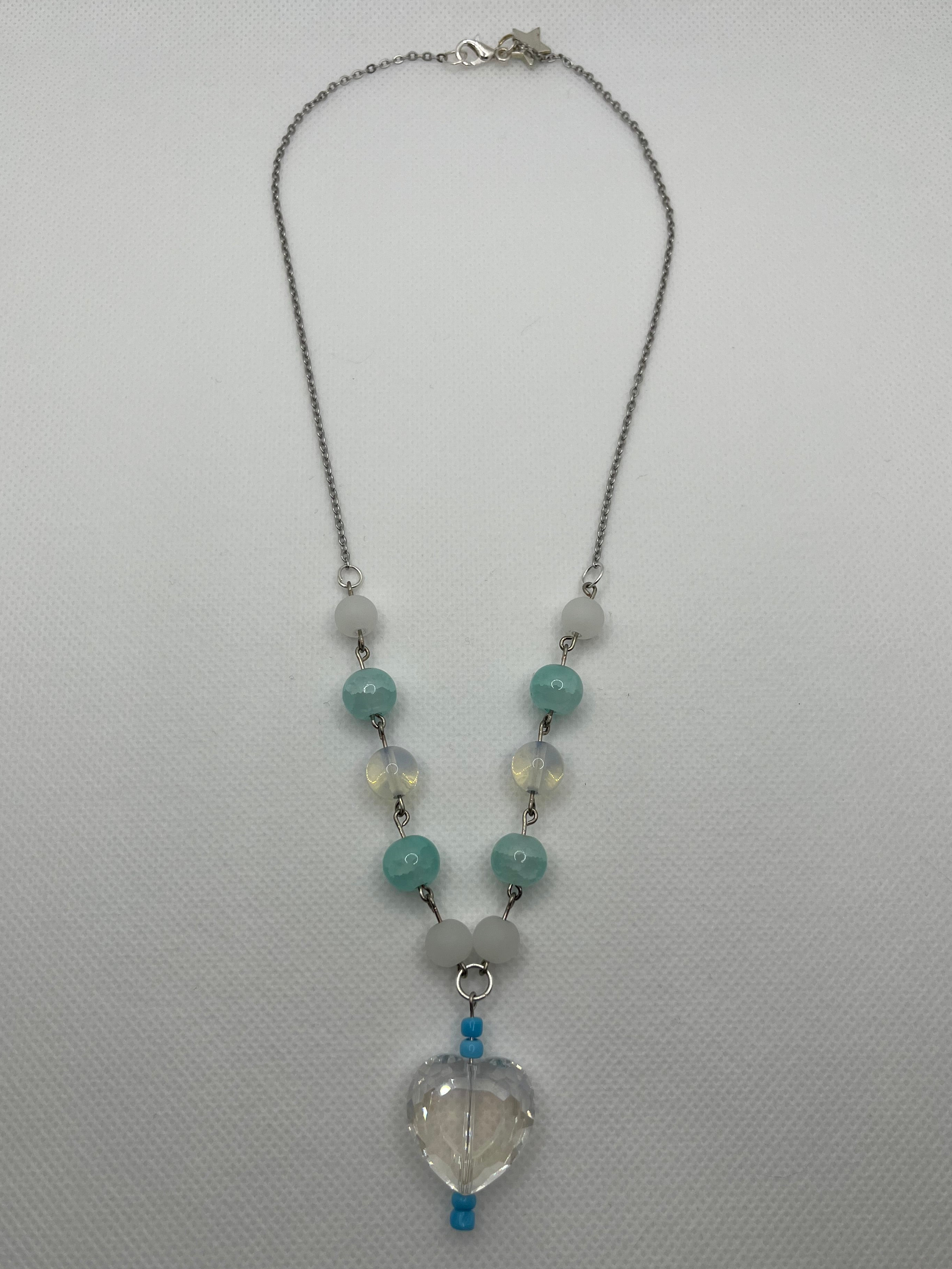 Blue, white, and clear necklace with a heart-shaped pendant laid flat against a white background.