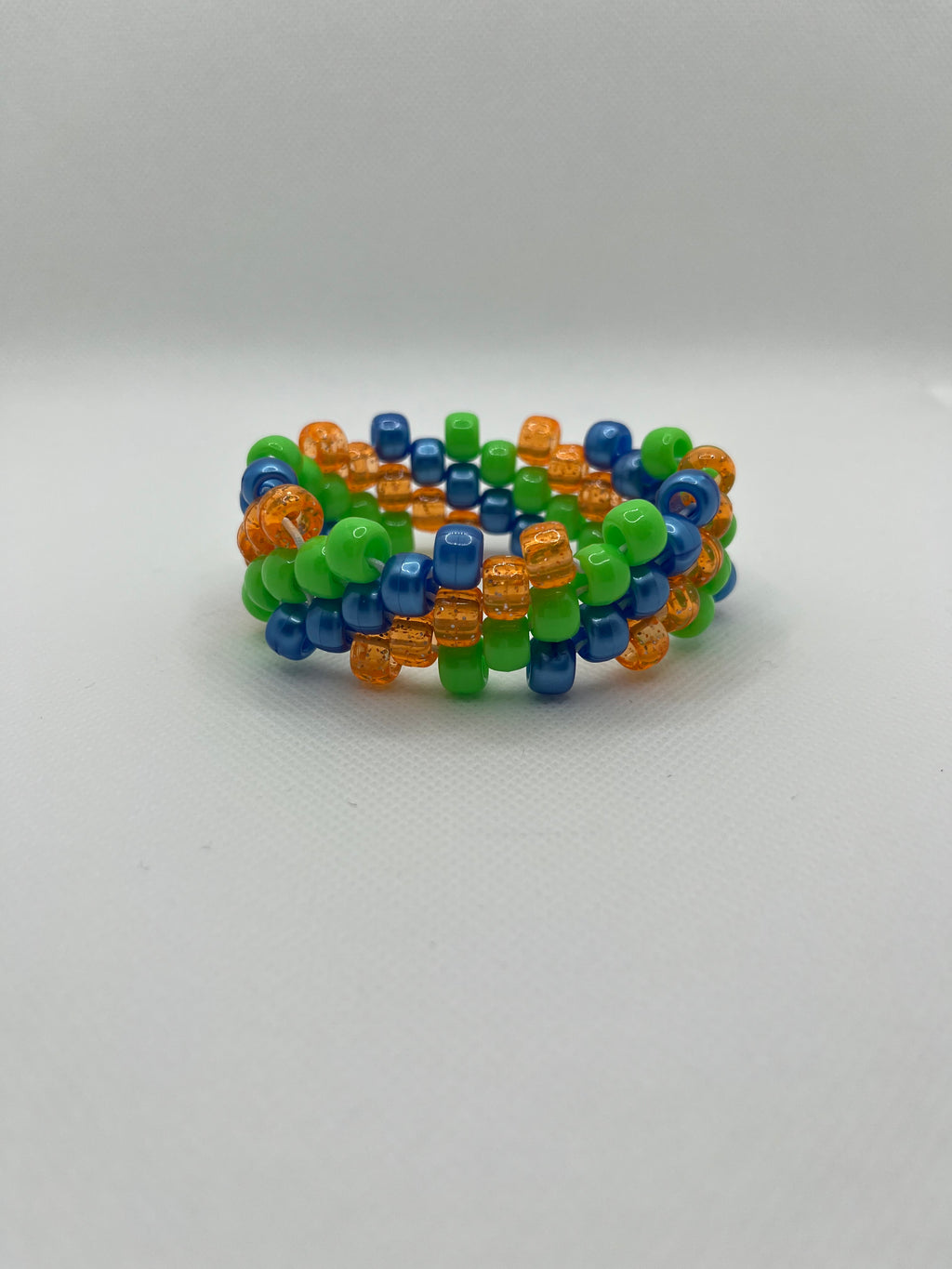 Orange, blue, and green spiral small beaded cuff bracelet against a white background