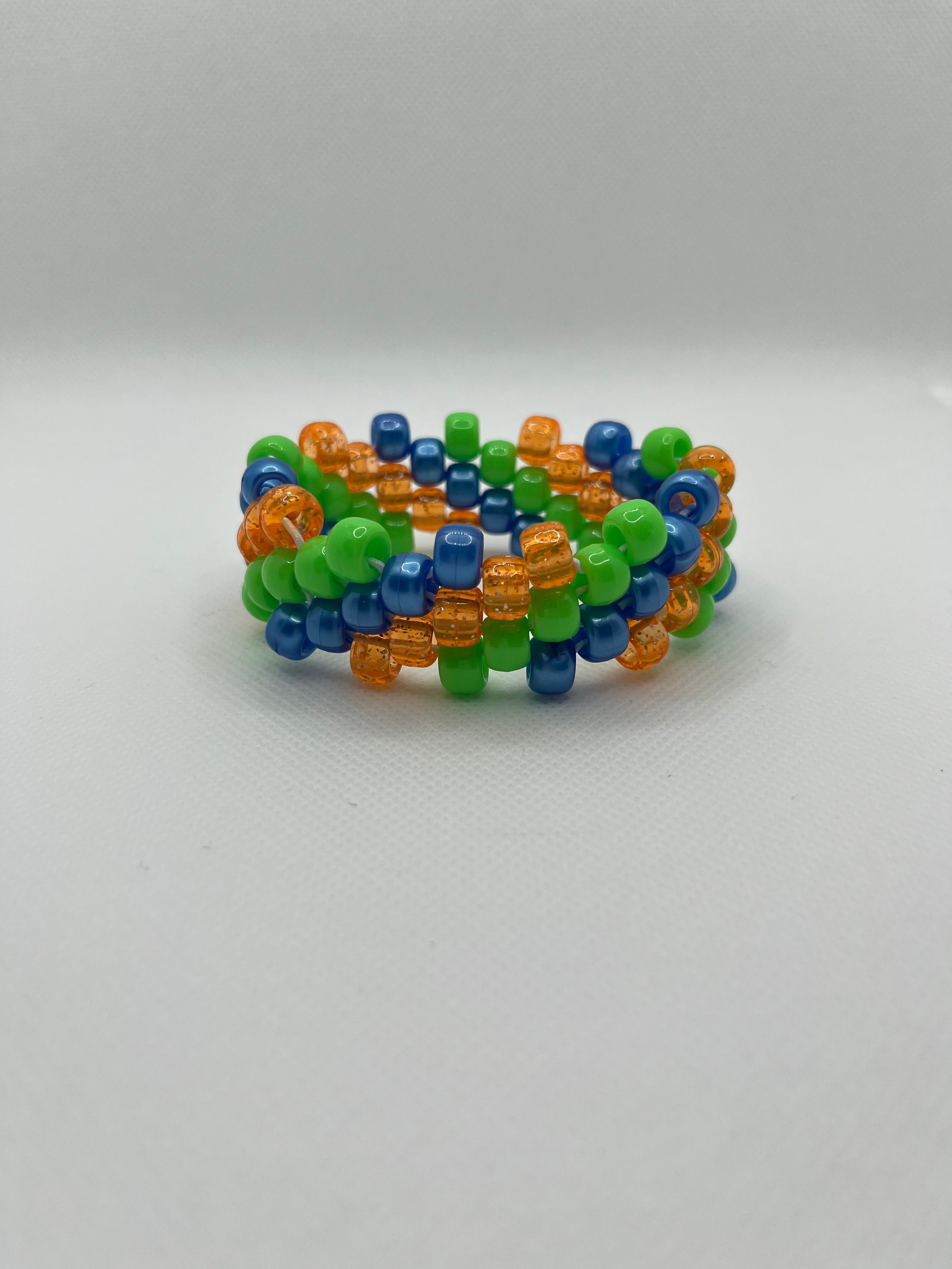 Orange, blue, and green spiral small beaded cuff bracelet against a white background