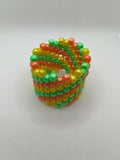 Orange, yellow, and green spiral beaded cuff bracelet against a white background