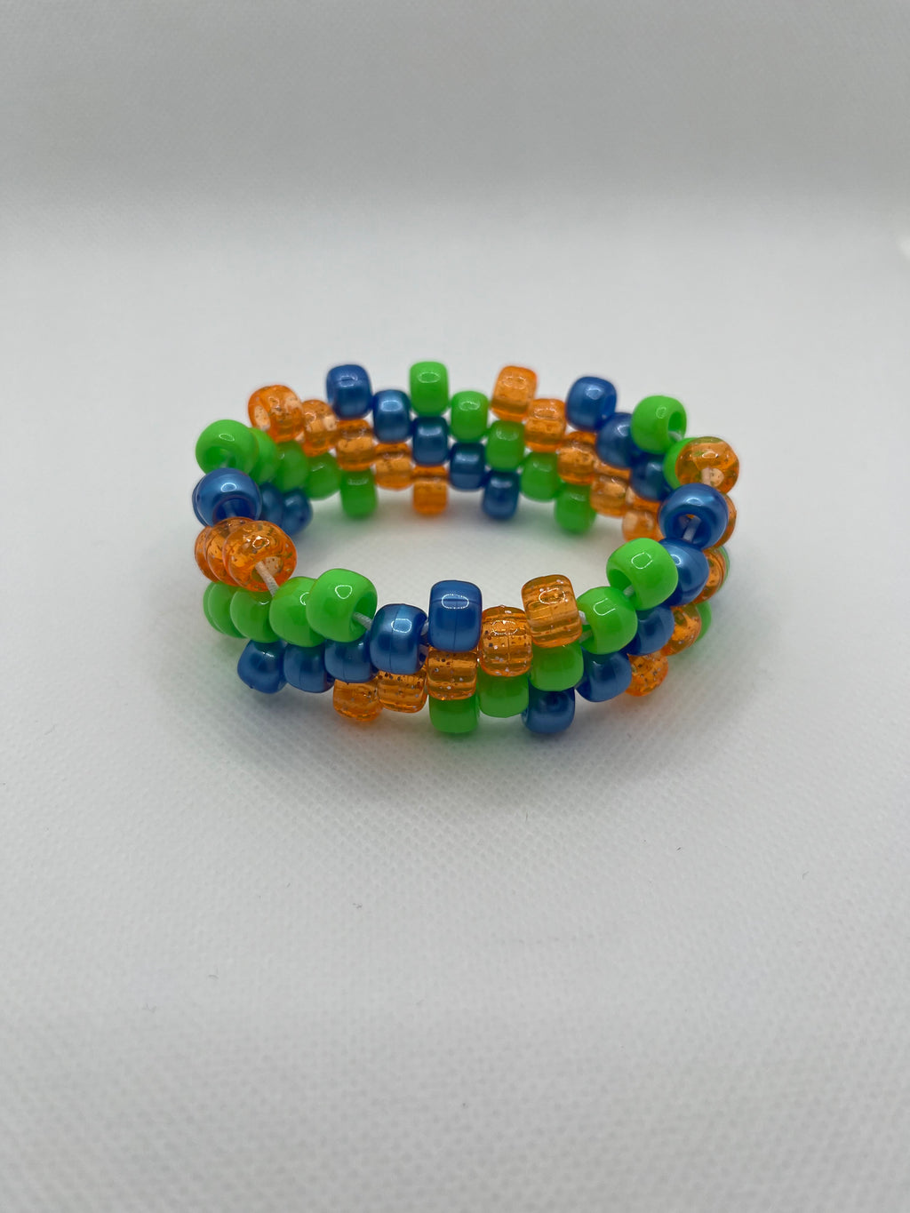 Orange, blue, and green spiral small beaded cuff bracelet against a white background