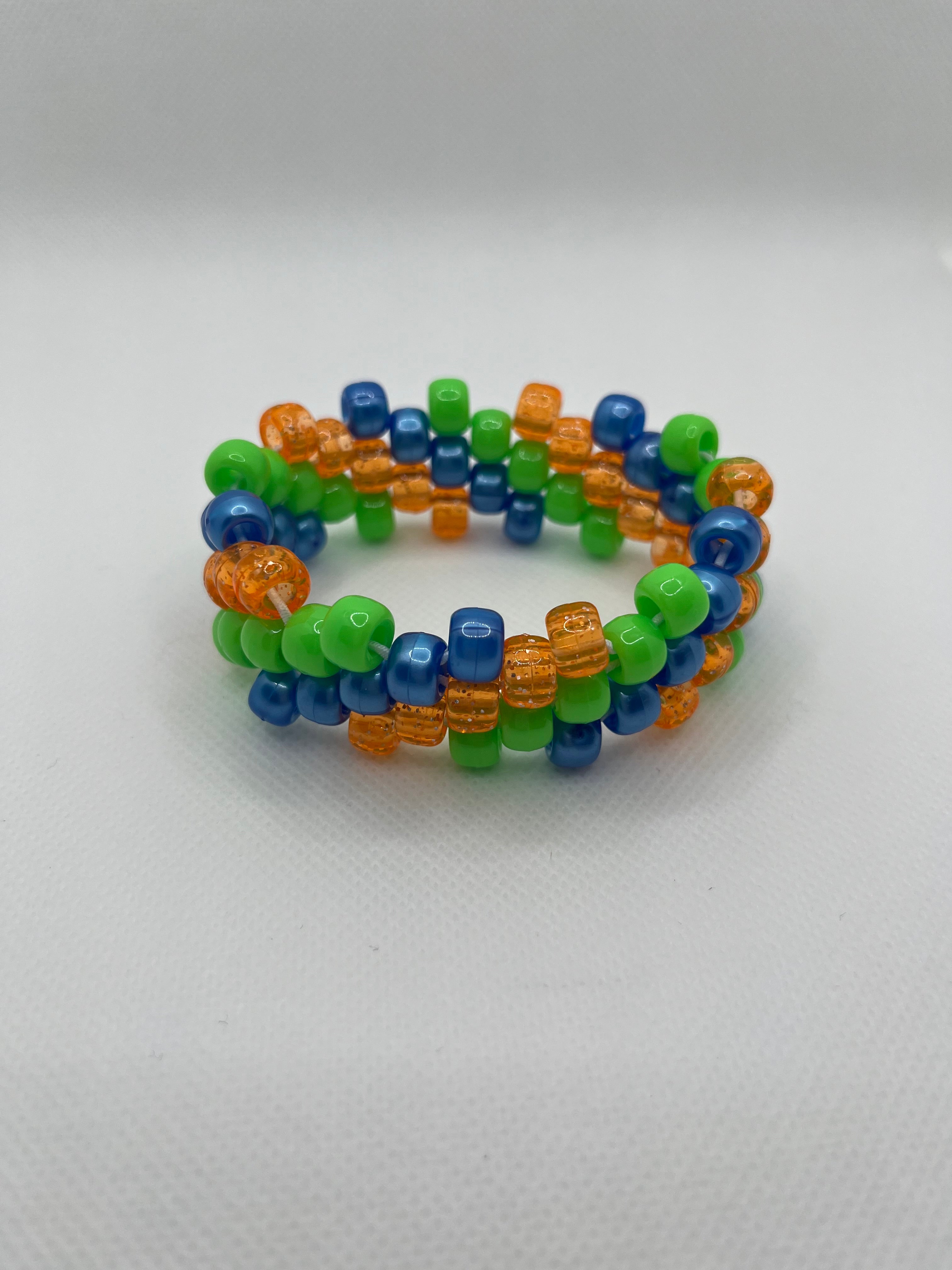 Orange, blue, and green spiral small beaded cuff bracelet against a white background