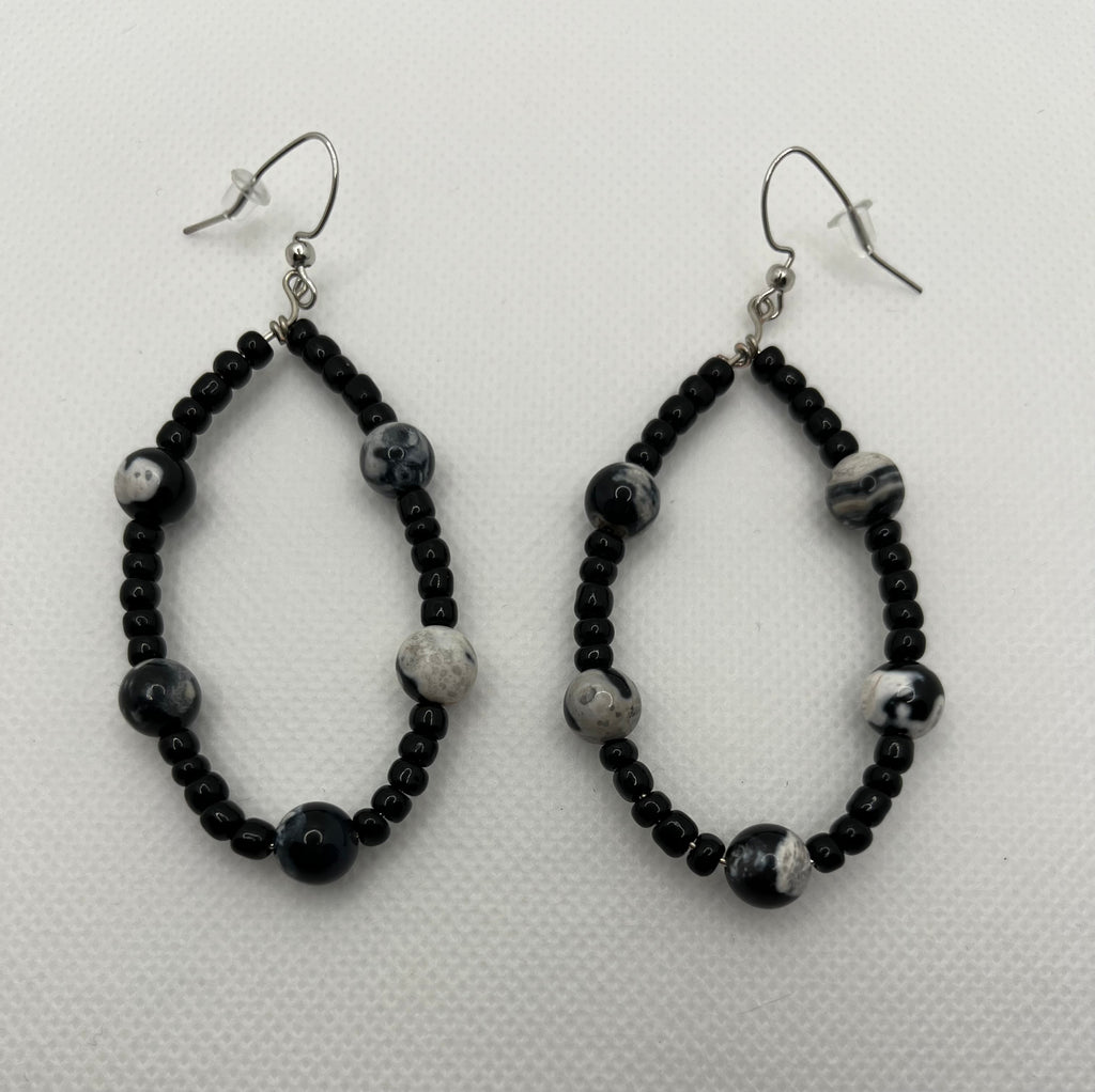 Black seed beaded earrings with black and white faux stones throughout against a white background