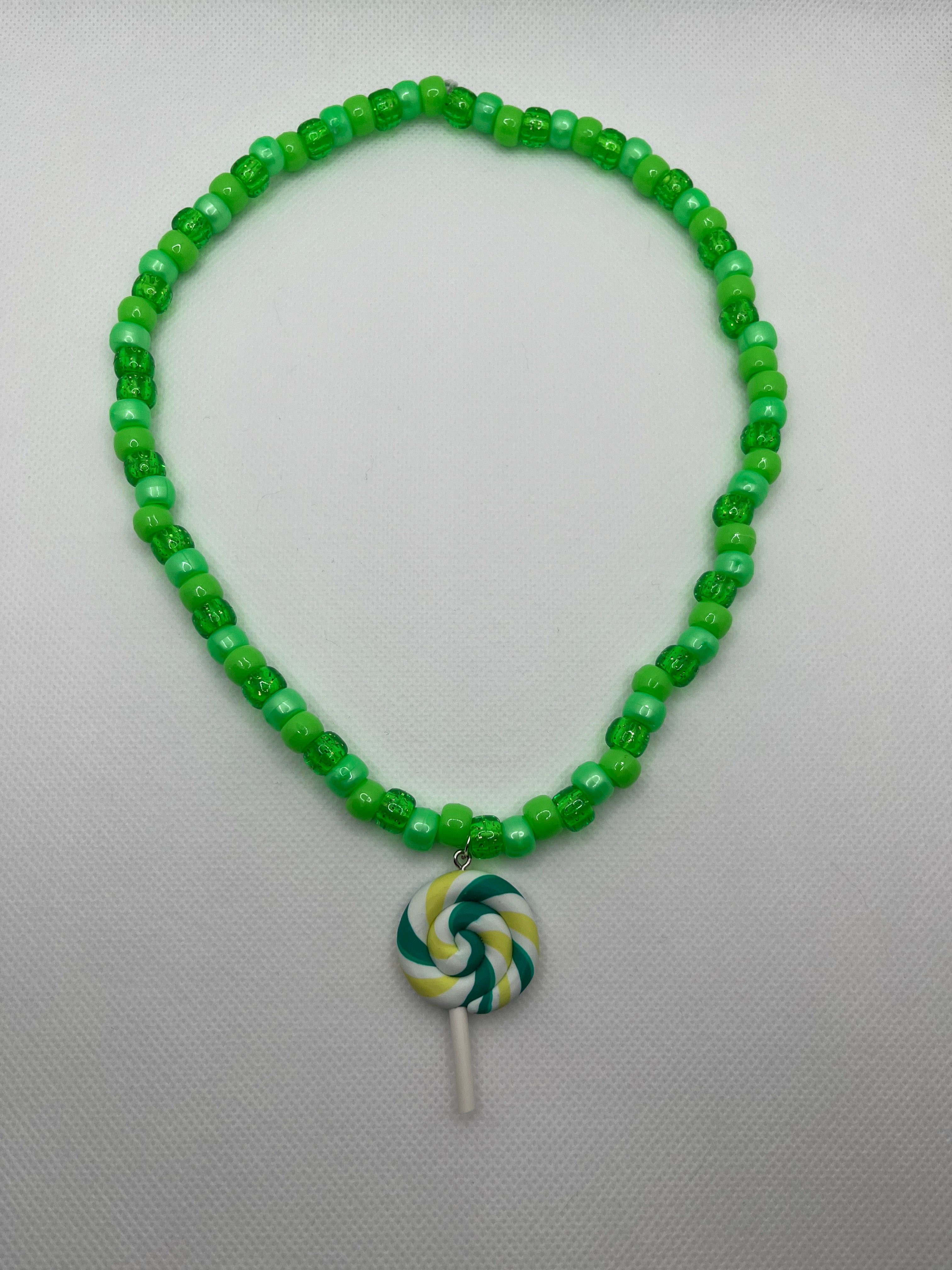 Green beaded necklace with green lollipop pendant on a white background