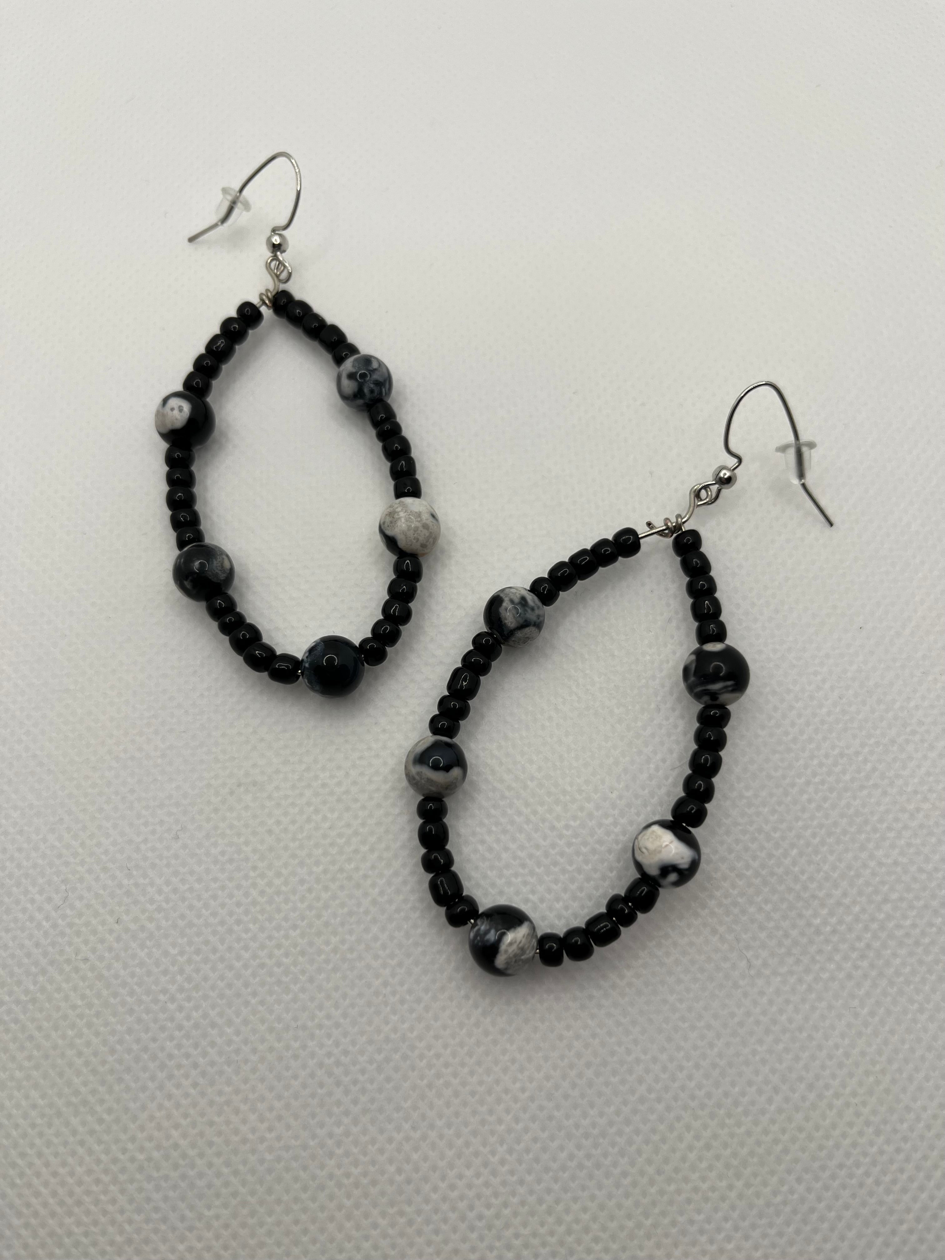Black seed beaded earrings with black and white faux stones throughout against a white background