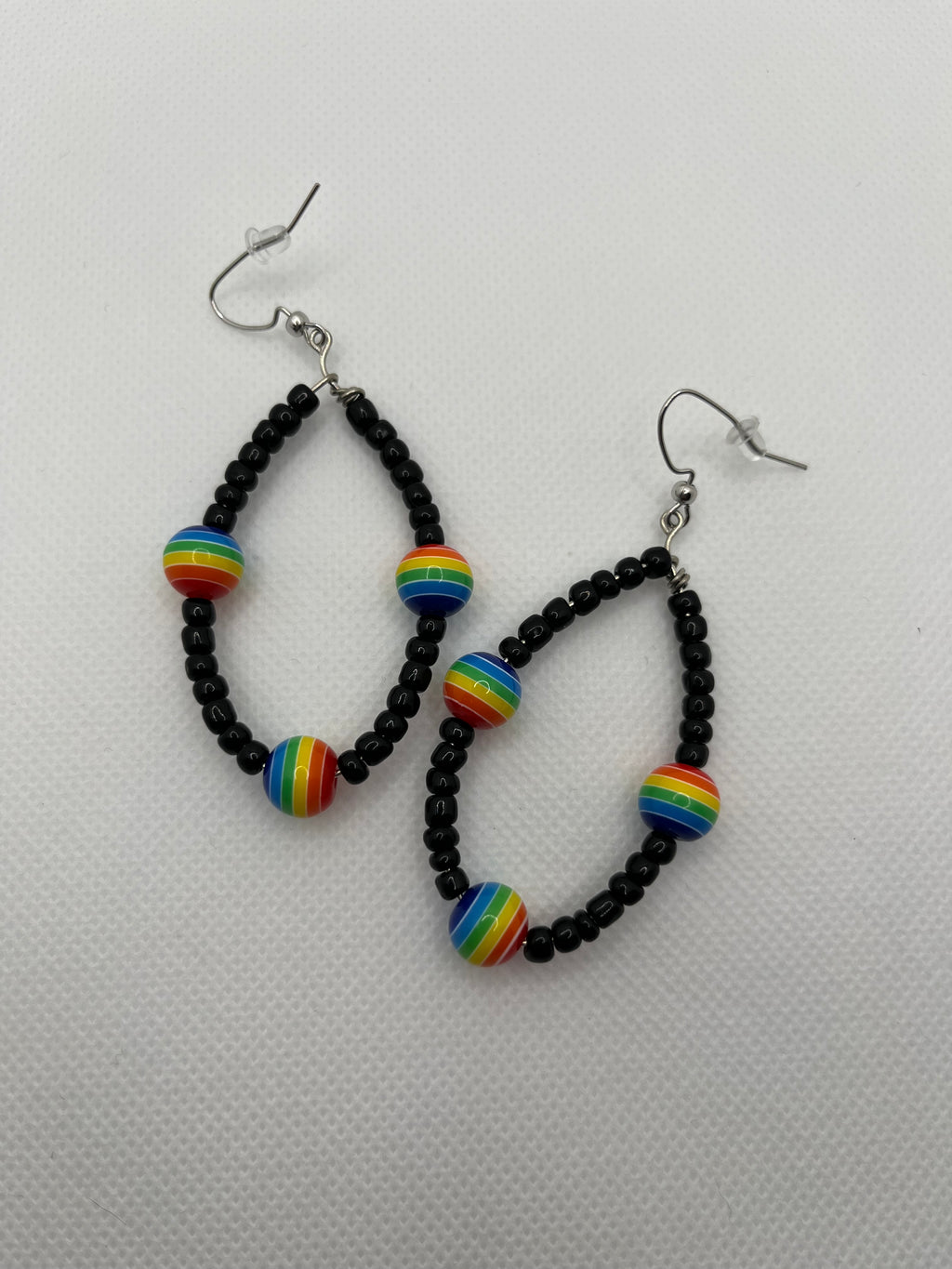 Black seed beads with rainbow beads throughout on earrings against a white background