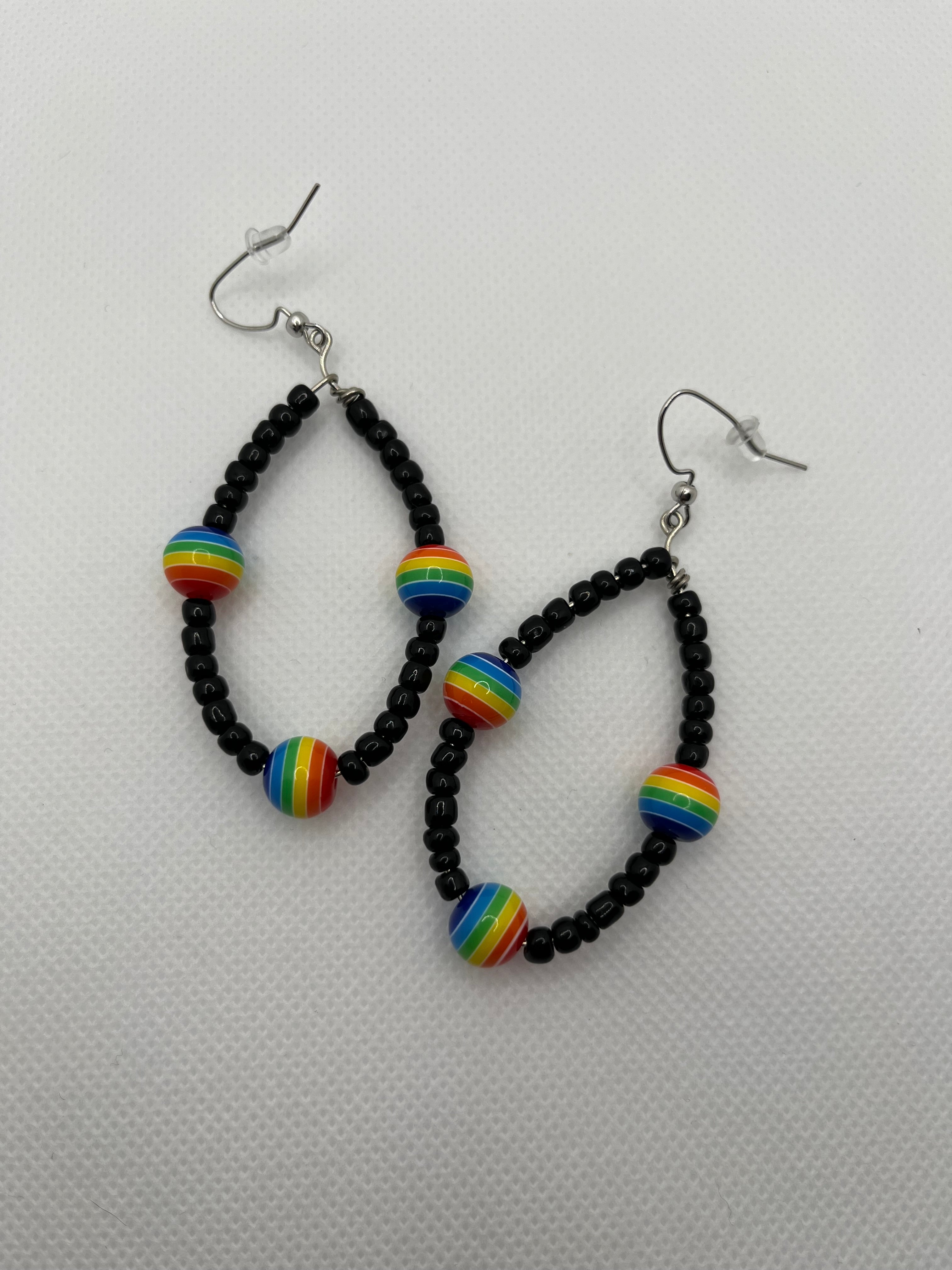 Black seed beads with rainbow beads throughout on earrings against a white background