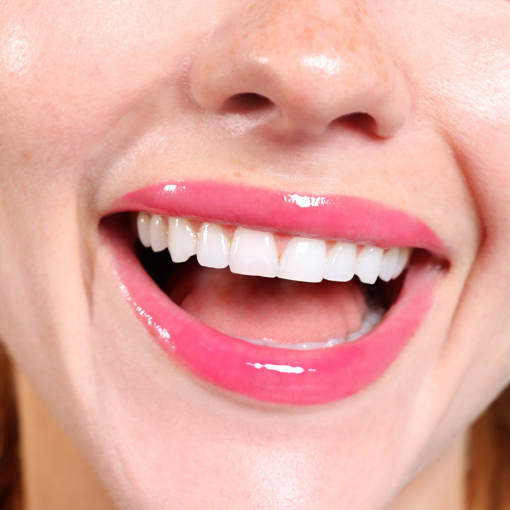 Close-up of a person with bright pink lips and white teeth.