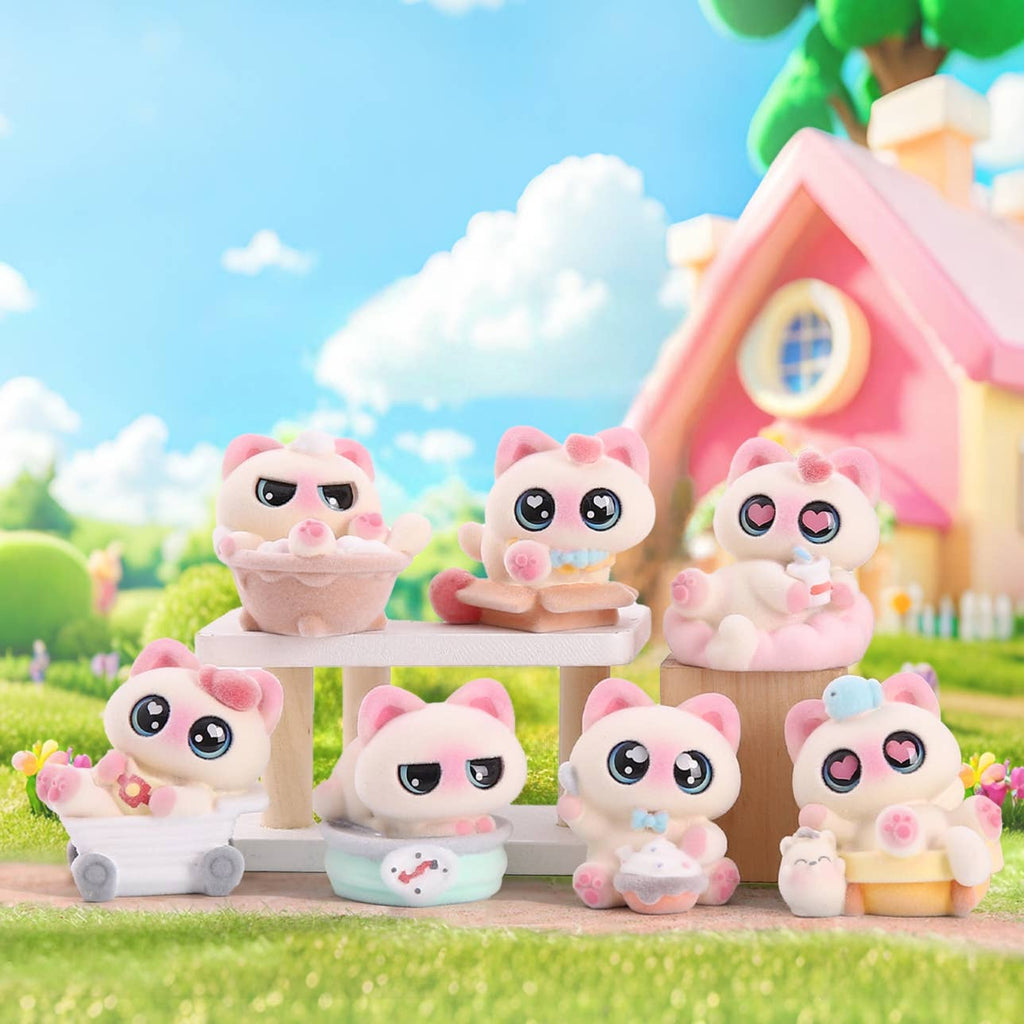 Set of pink cat-themed figurines in a whimsical outdoor setting with a house and trees.