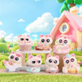 Set of pink cat-themed figurines in a whimsical outdoor setting with a house and trees.