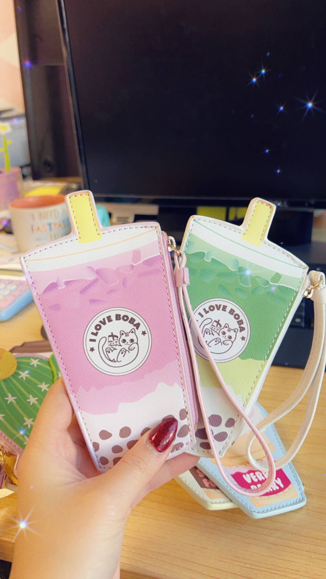 Two small bubble tea wristlets held by a hand against a desk background.