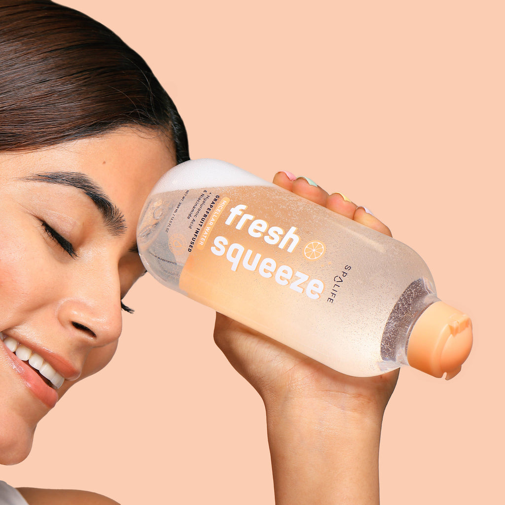 Person holding a 'fresh squeeze' bottle against a beige background