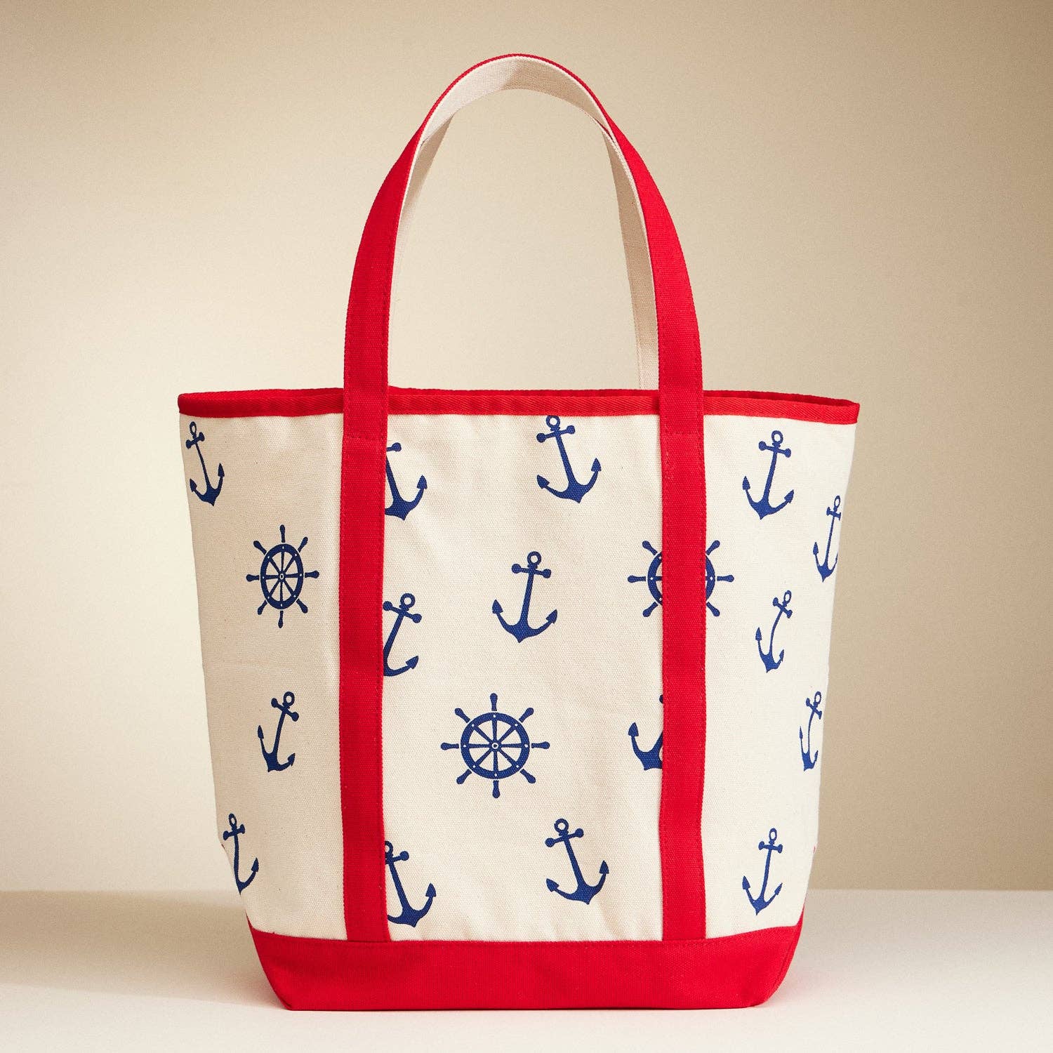 Tote bag with nautical pattern featuring anchors and ship wheels on a beige background