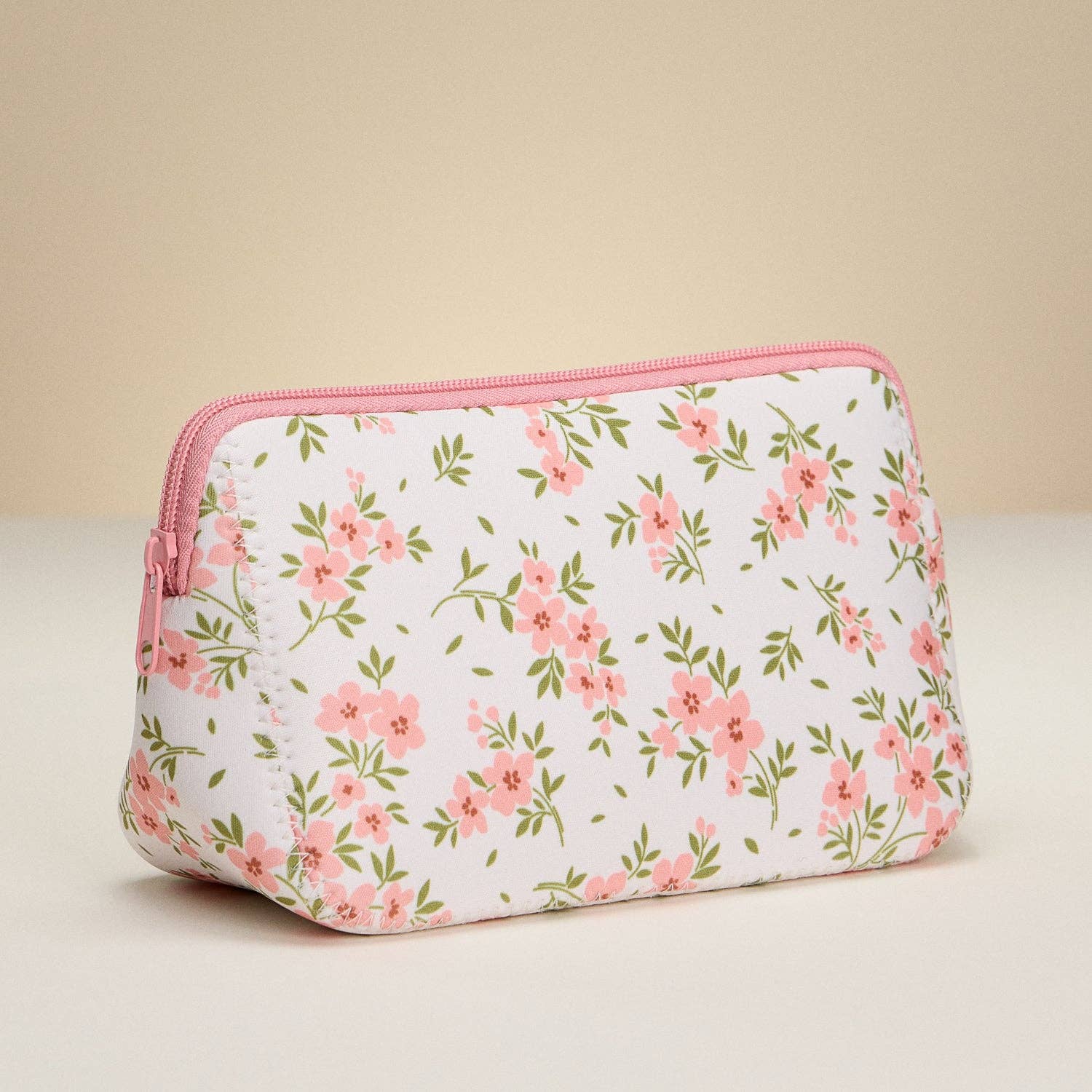 Floral-patterned pouch with pink zipper on a beige background