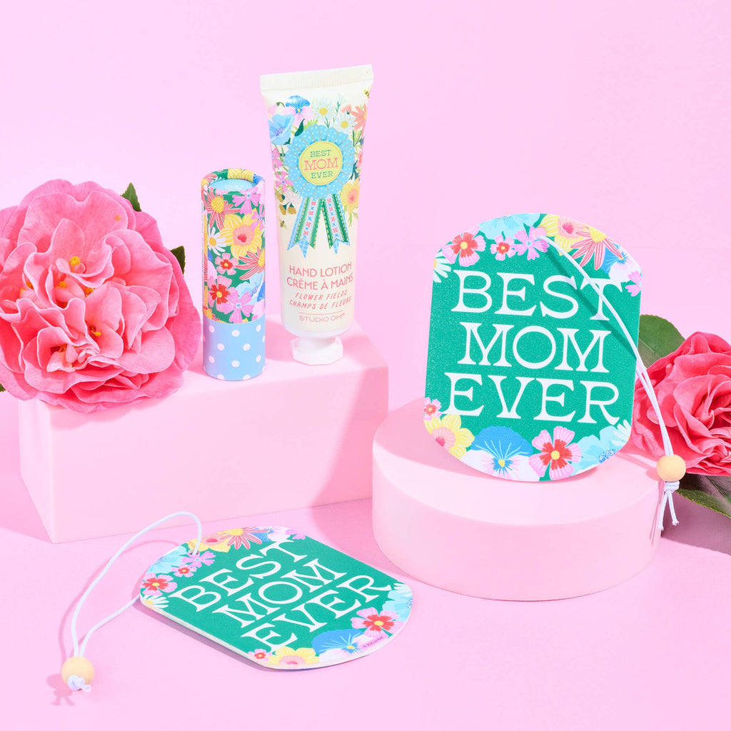 Gift set with 'Best Mom Ever' card, lotion, and flowers on a pink background