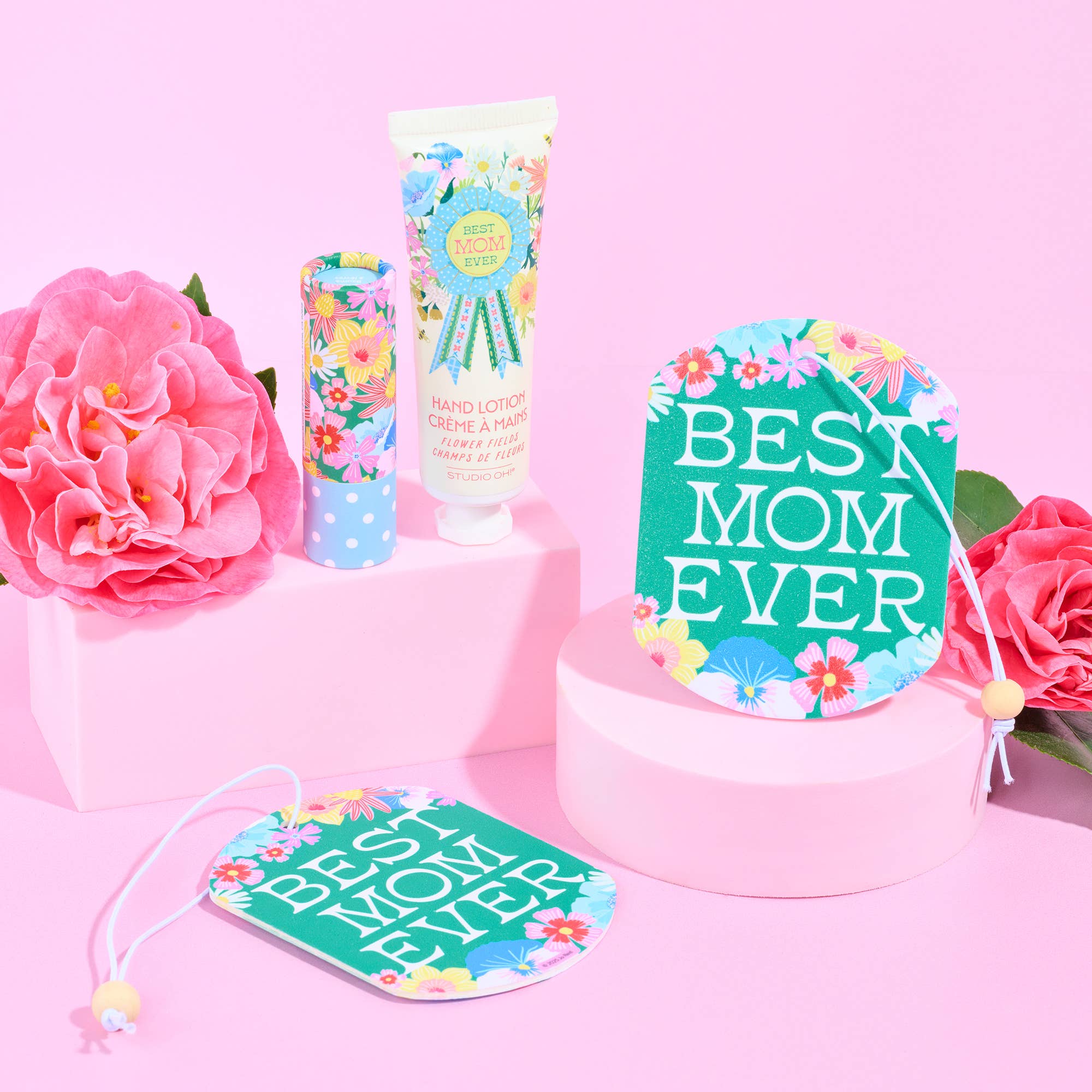 Gift set with 'Best Mom Ever' card, lotion, and flowers on a pink background