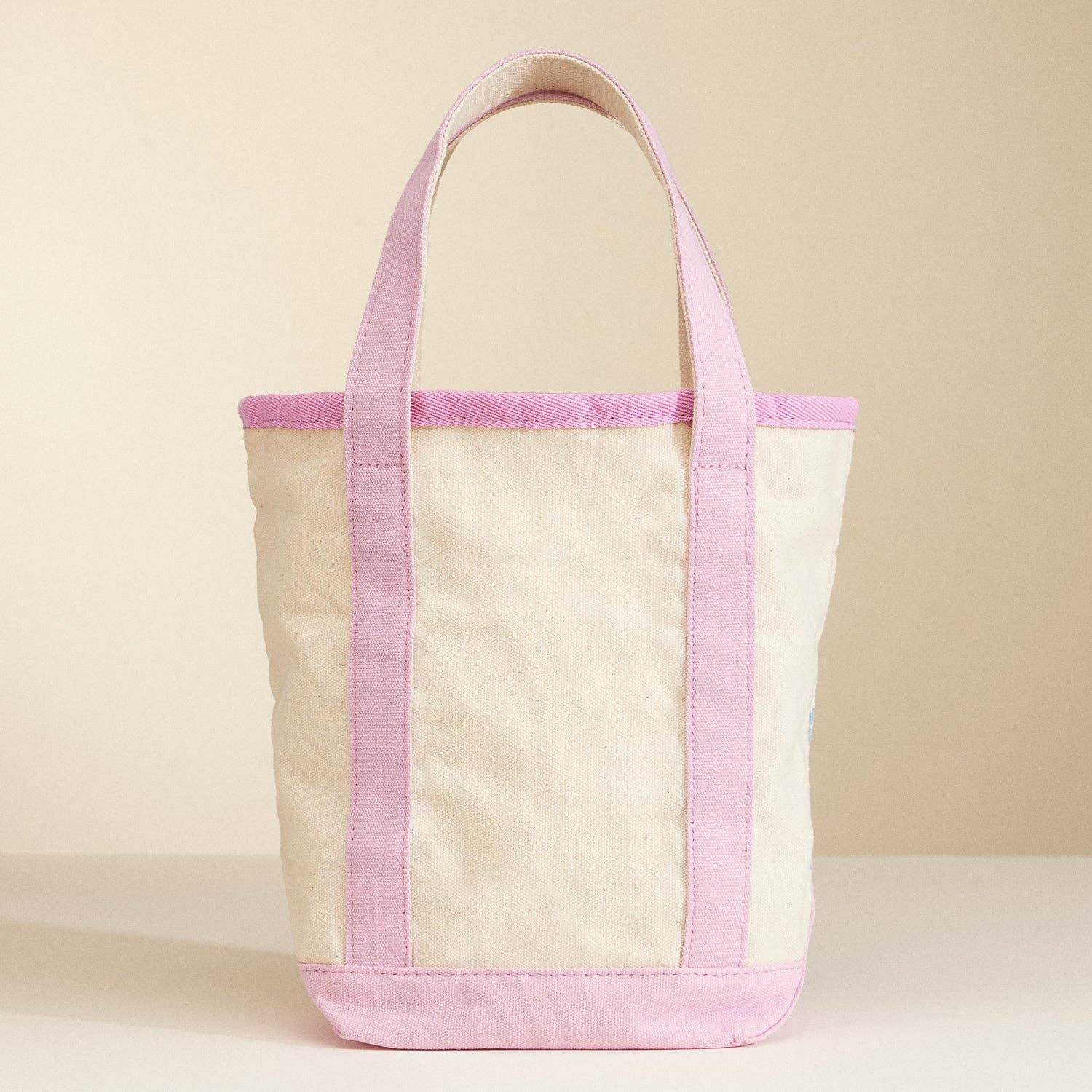 Canvas tote bag with pink accents on a beige background