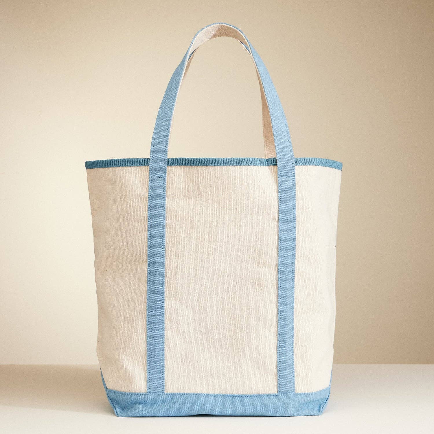 Beige tote bag with light blue accents on a beige background